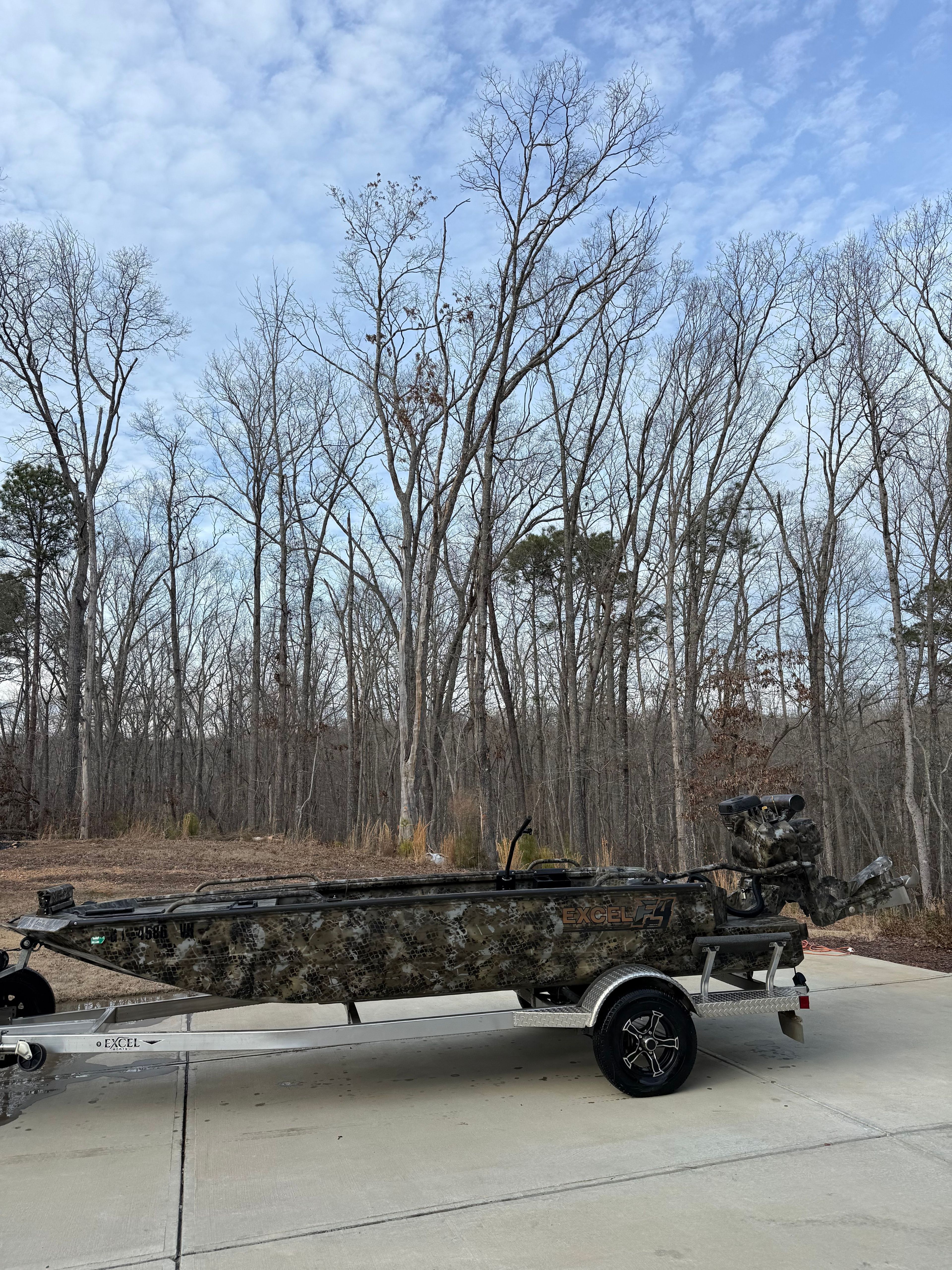 2024 Excel 1754 Shallow Water F4 boat on trailer in wooded area.