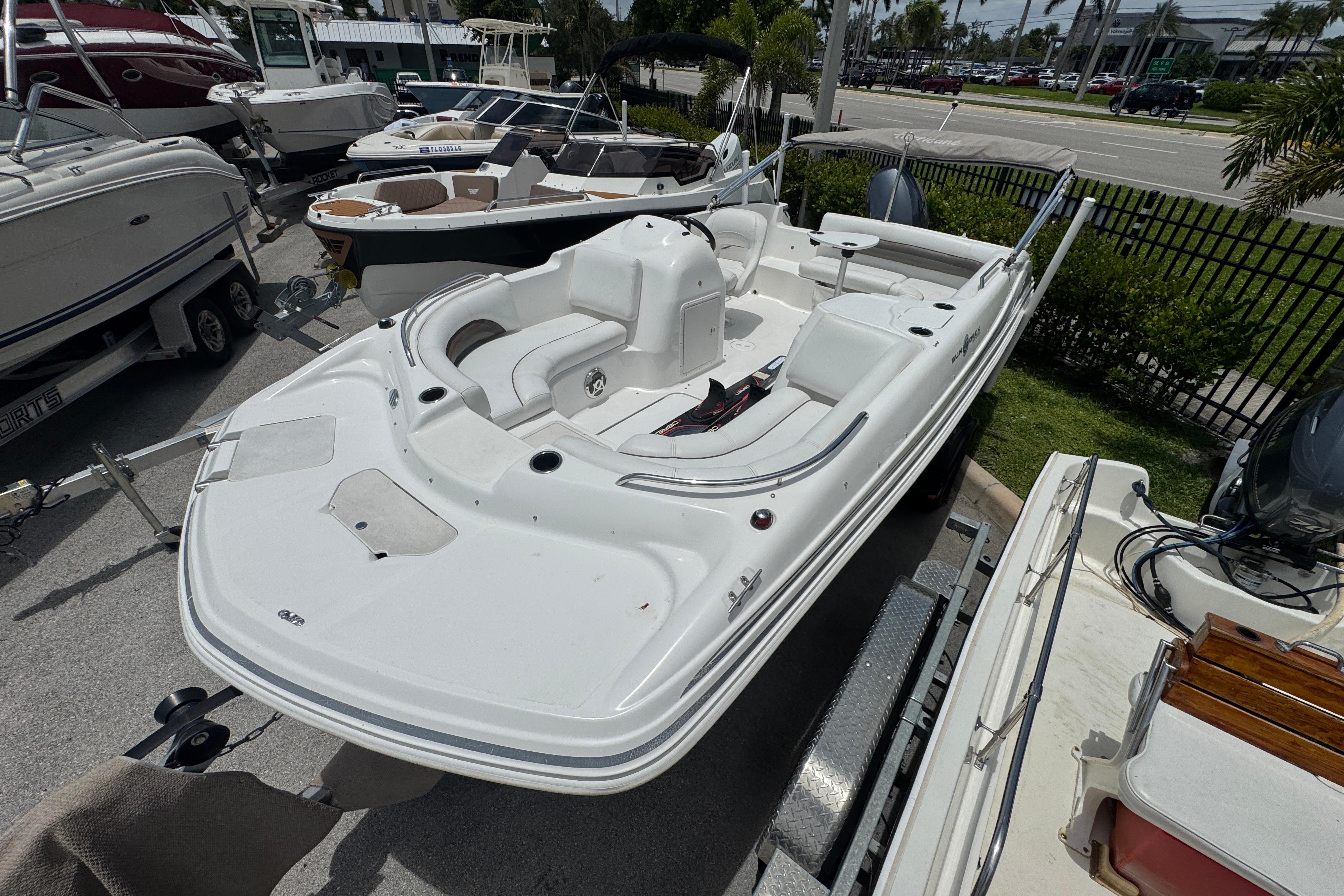 2013 Hurricane SunDeck Sport 188 OB boat on trailer, parked among other boats.