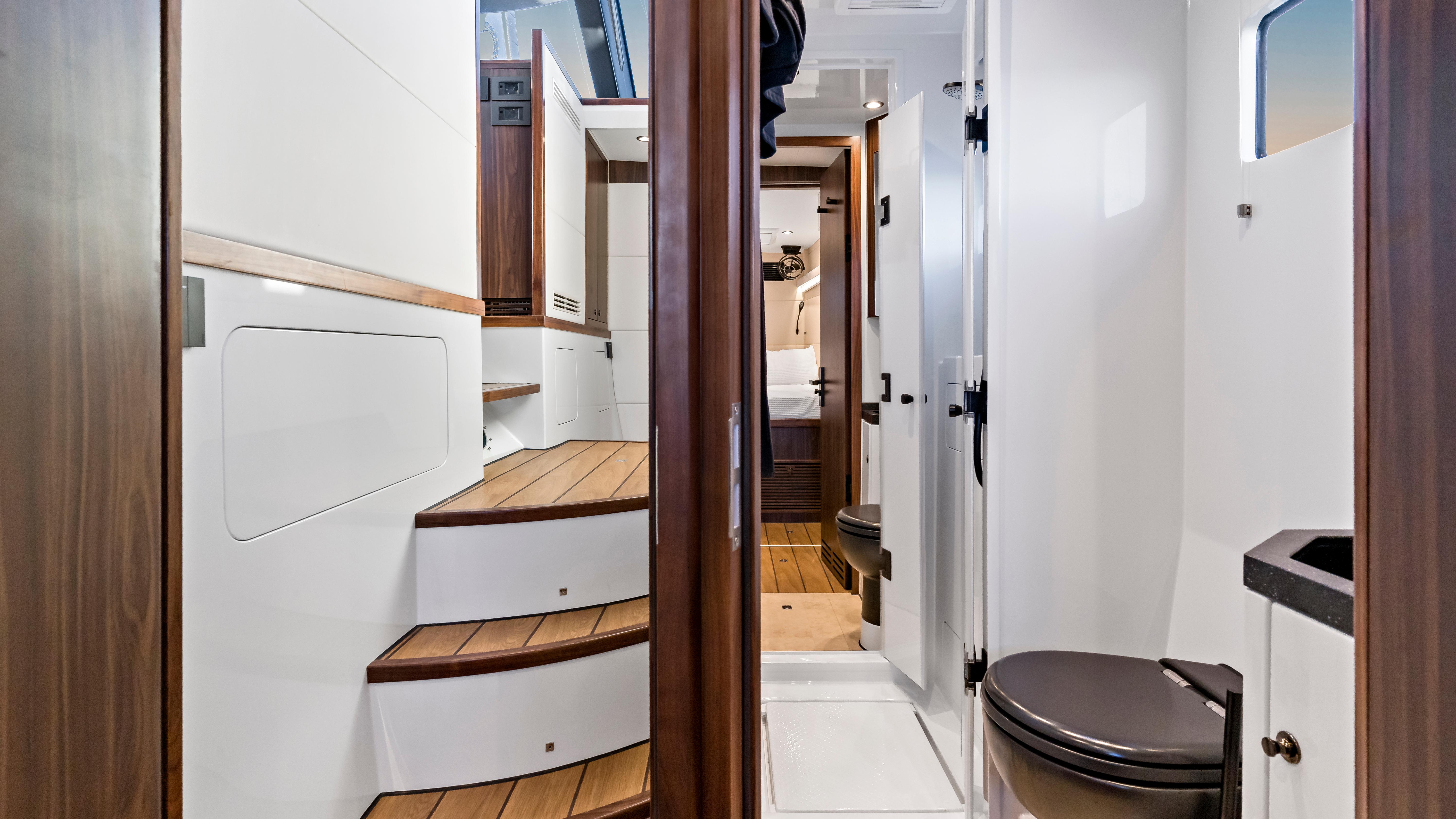 Interior of 2022 HH Catamarans 50 SC, featuring wooden stairs and modern bathroom.