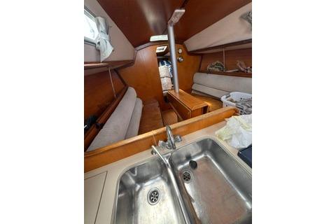 Interior of 1986 Beneteau First 305 sailboat, featuring a compact kitchen and cozy seating area.