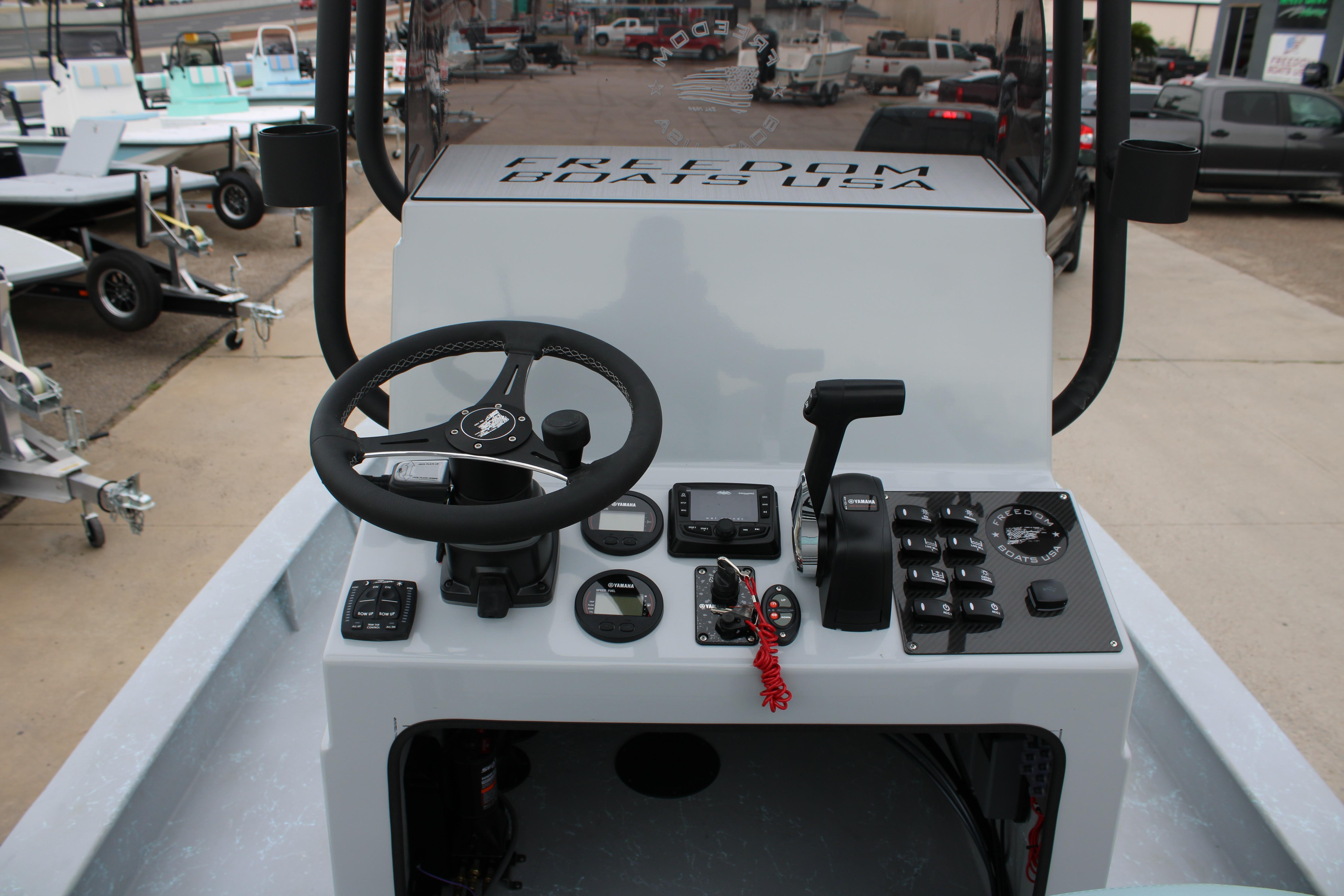 2026 Freedom Boats 24 Defender console with steering wheel and controls, parked on a trailer.