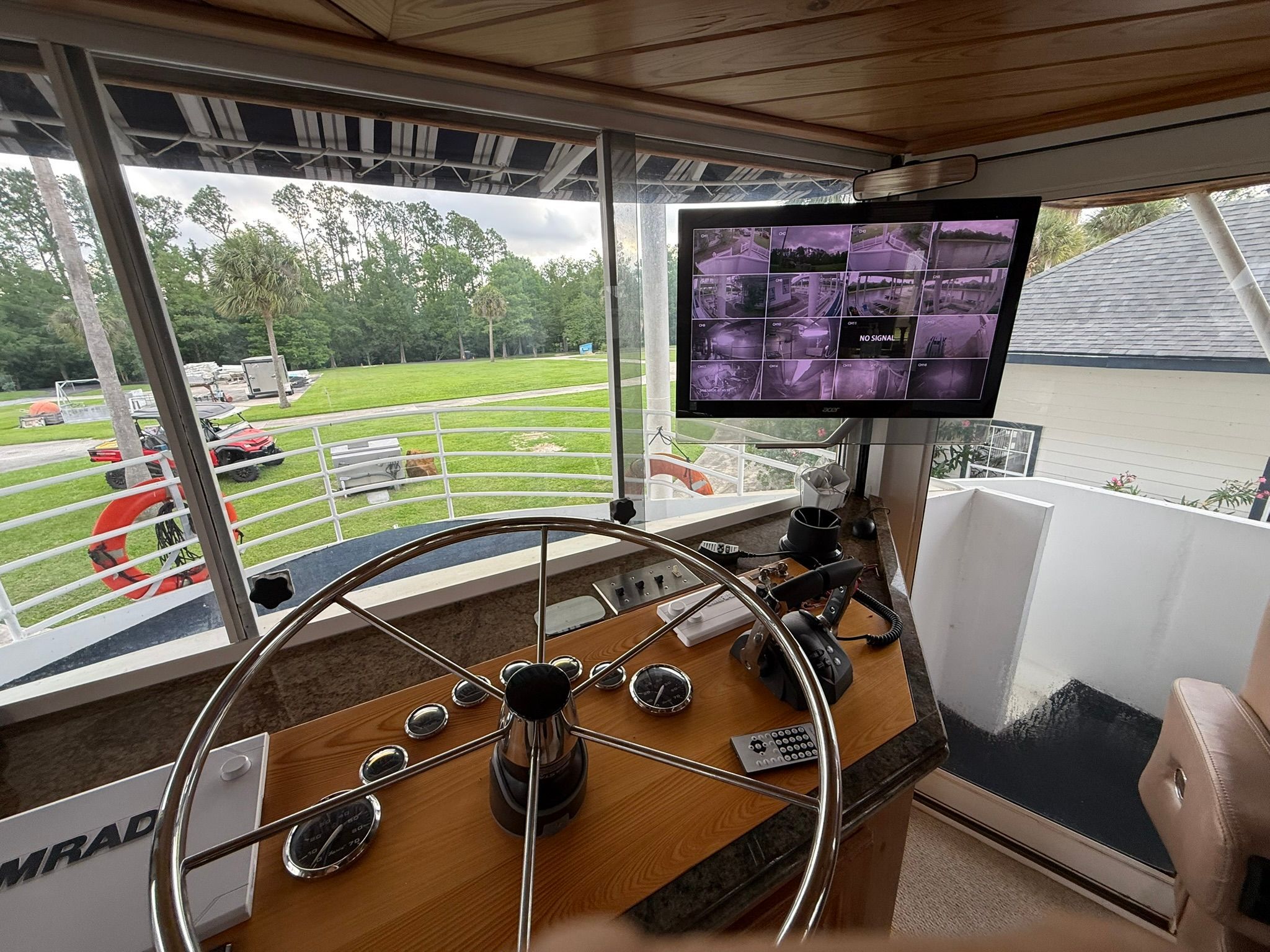 The image shows a boat's helm with a large steering wheel and a monitor.