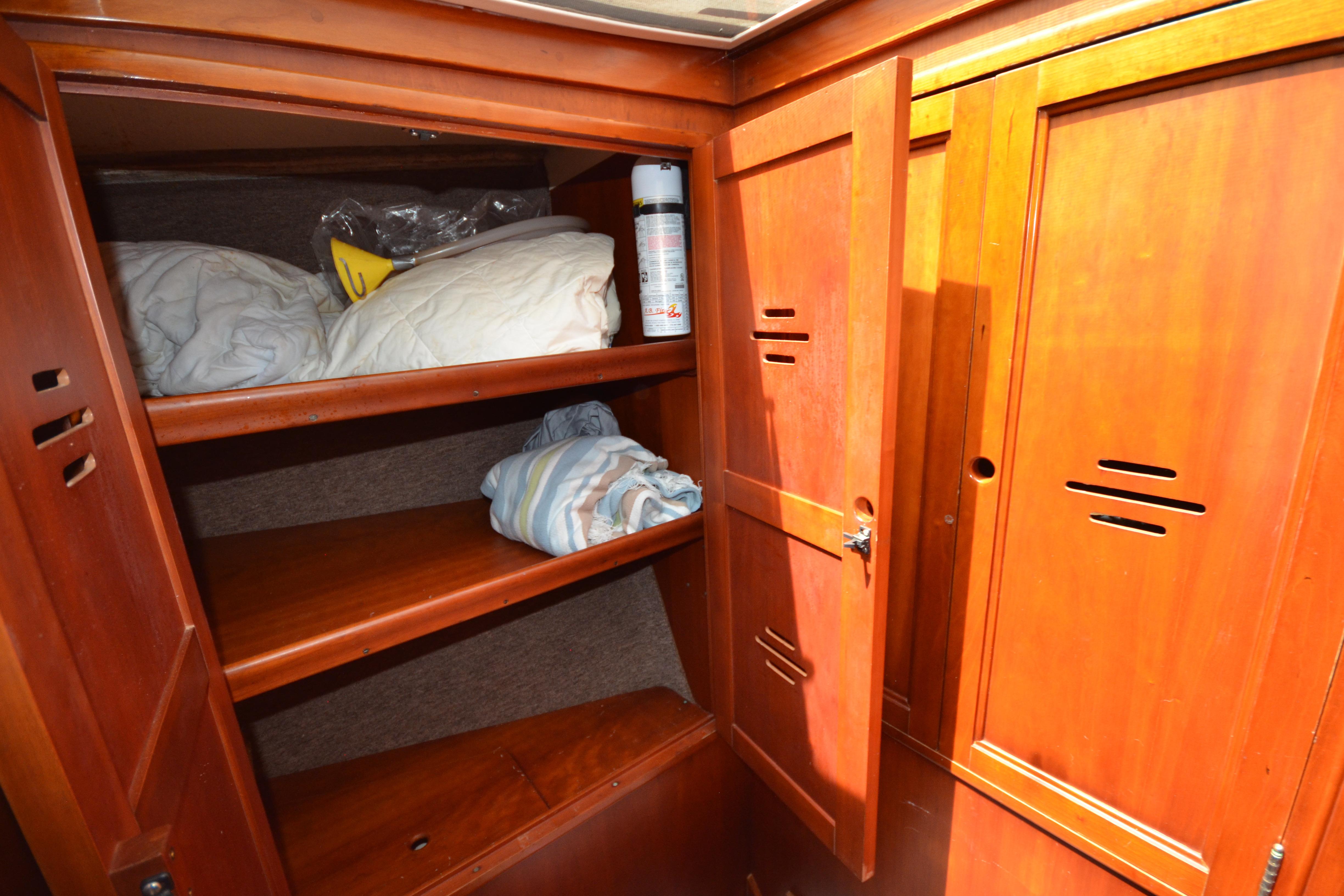 Wooden storage cabinet inside 1992 Hinckley Sou'wester 59 yacht, featuring shelves with bedding.