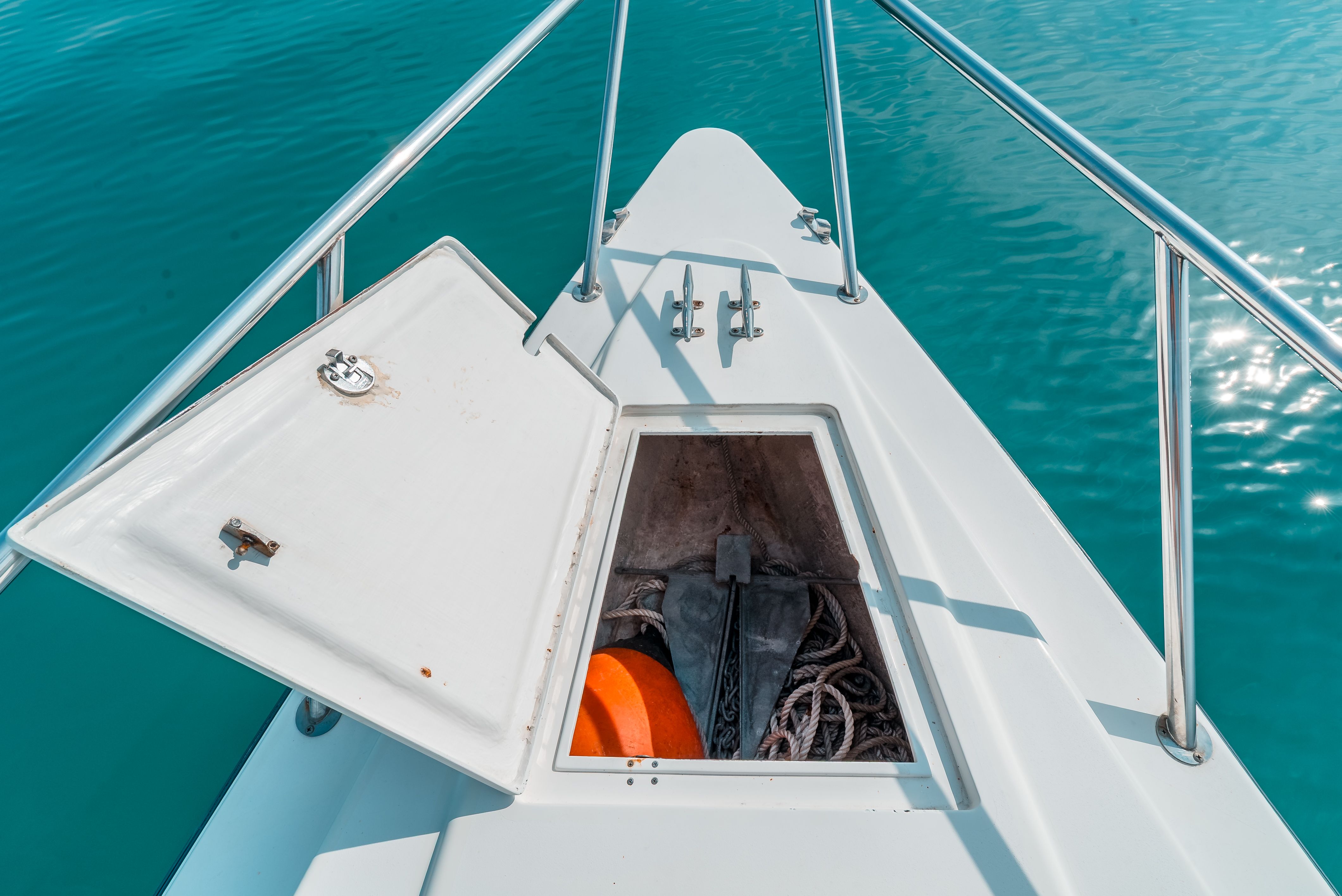 Bow of a boat with open storage compartment, anchor and rope visible.