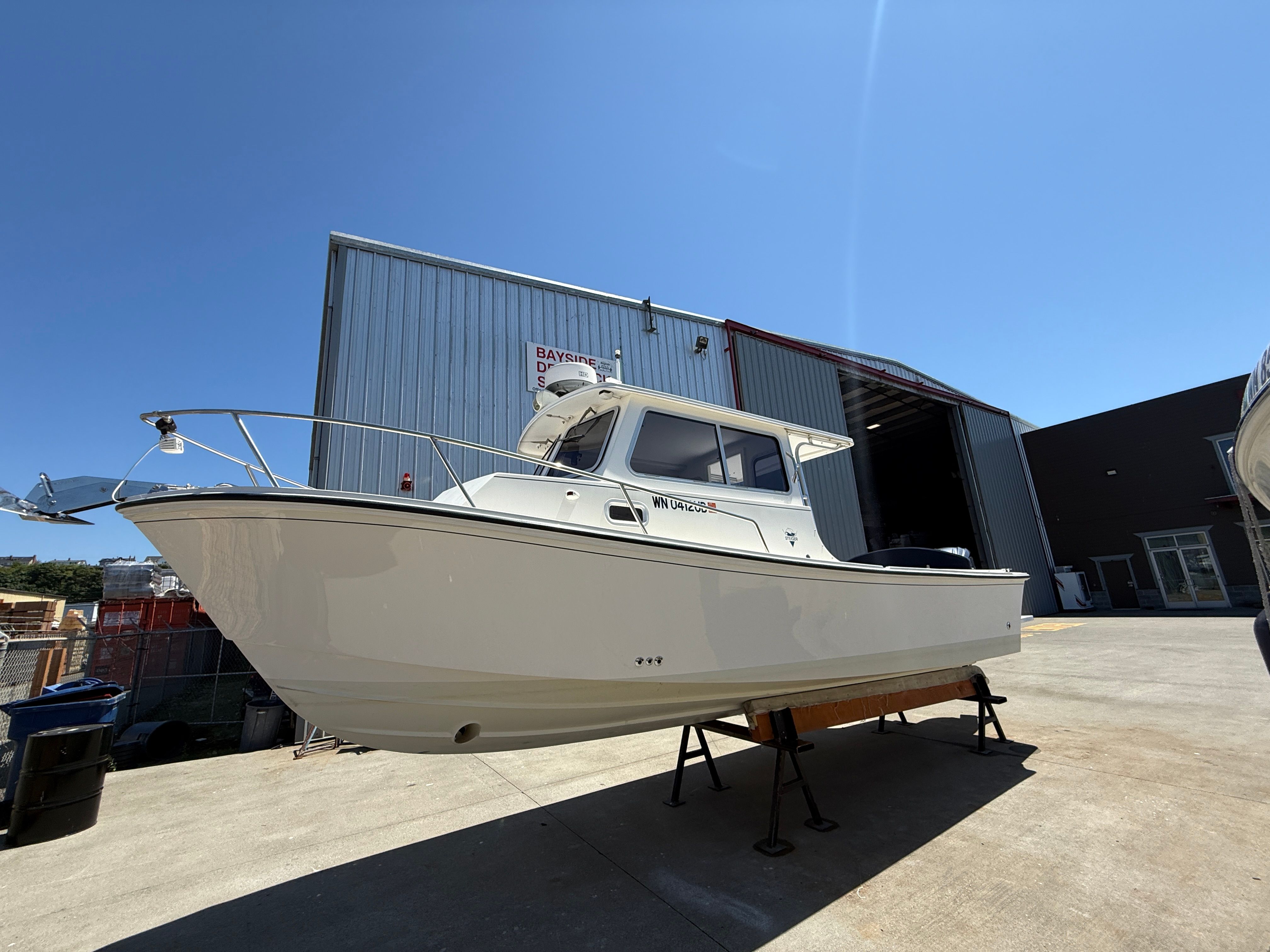 A 2015 Steiger Craft 255 Chesapeake boat is on a dry dock outside a warehouse.