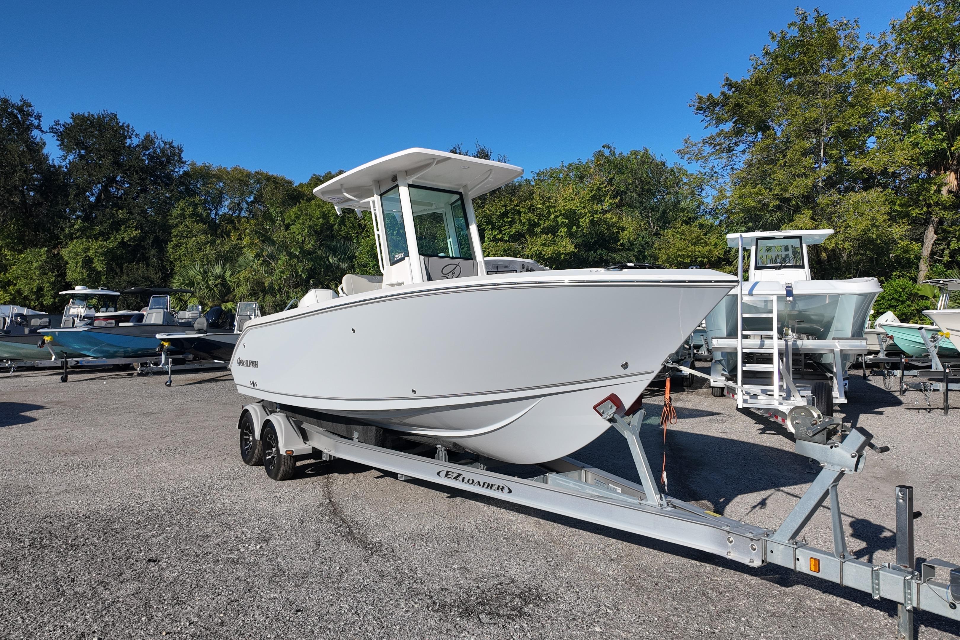 2026 Sailfish 232 CC boat on trailer in outdoor lot, surrounded by trees.