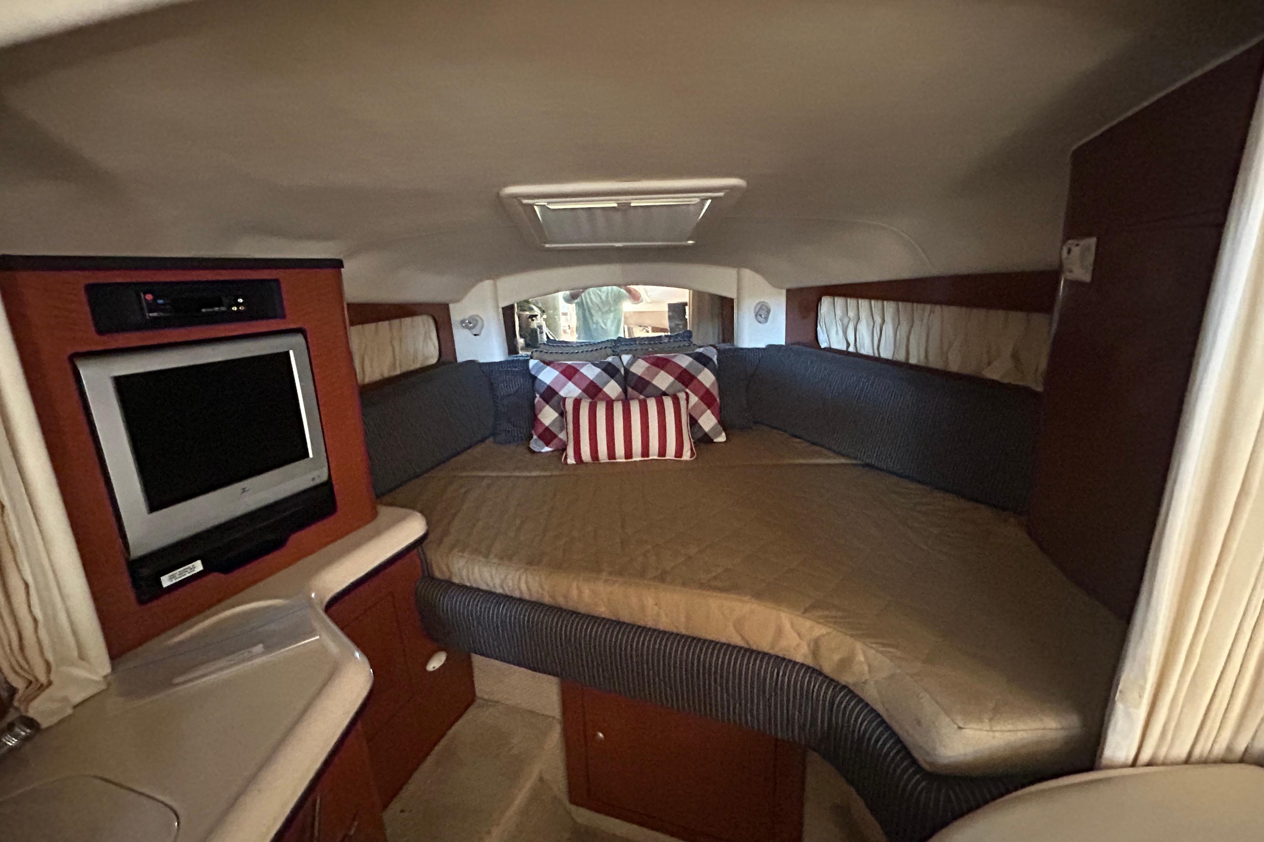 2005 Sea Ray 300 Sundancer cabin interior with bed, TV, and cozy decor.