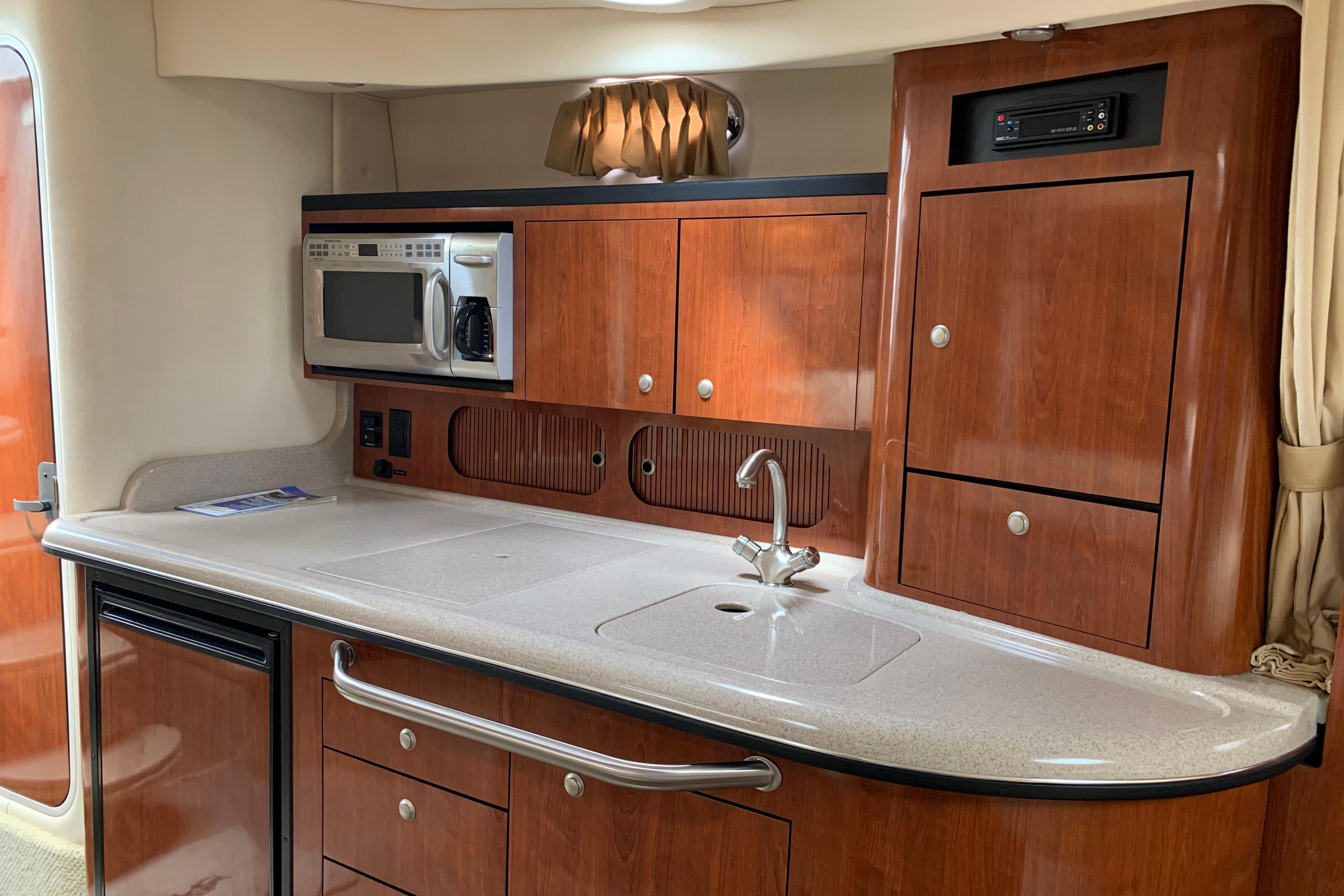 Luxurious 2007 Sea Ray 340 Sundancer yacht interior with modern kitchenette and wood cabinetry.