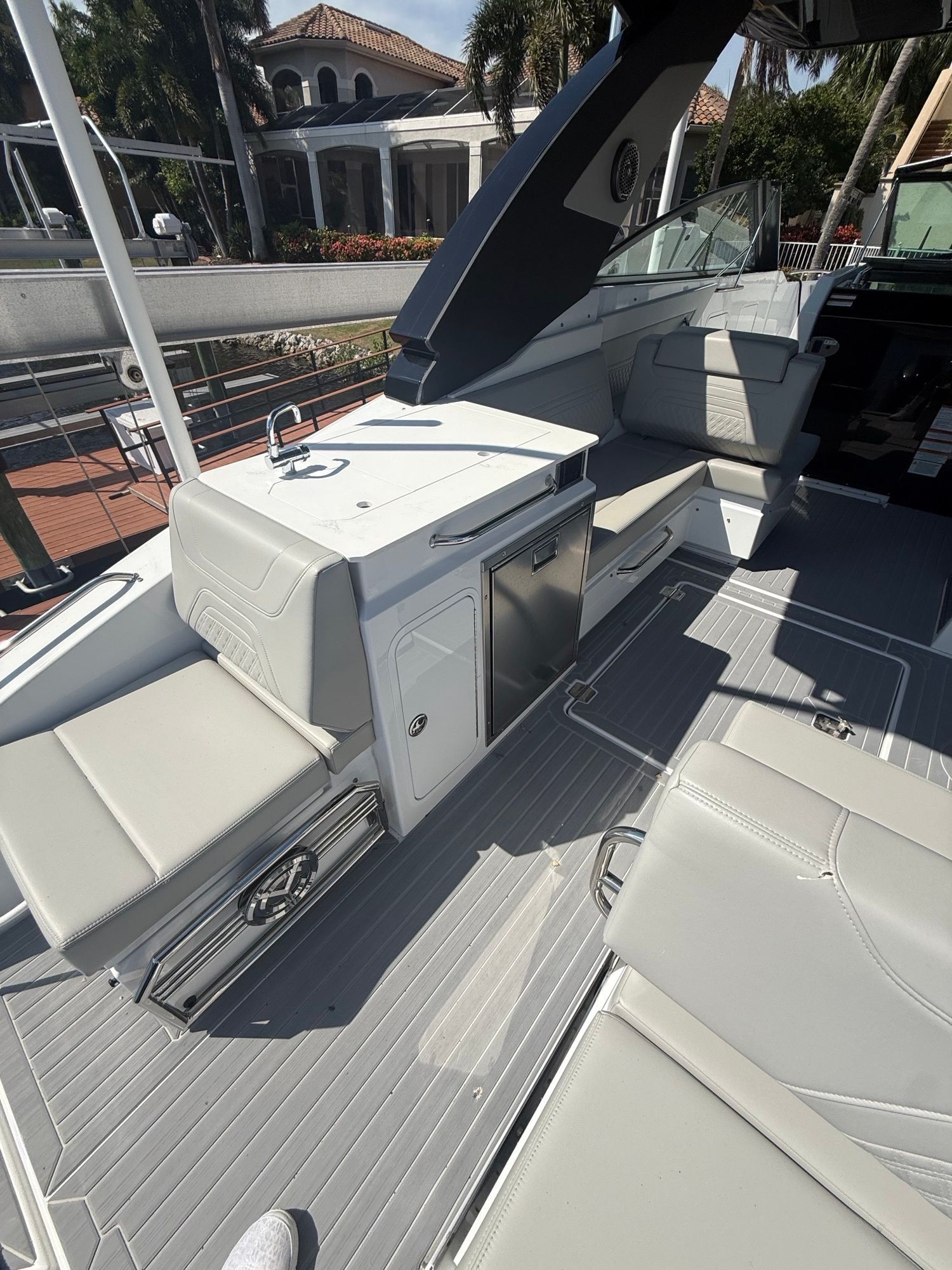 The image shows the deck of a luxury yacht with sleek seating and a small kitchenette.
