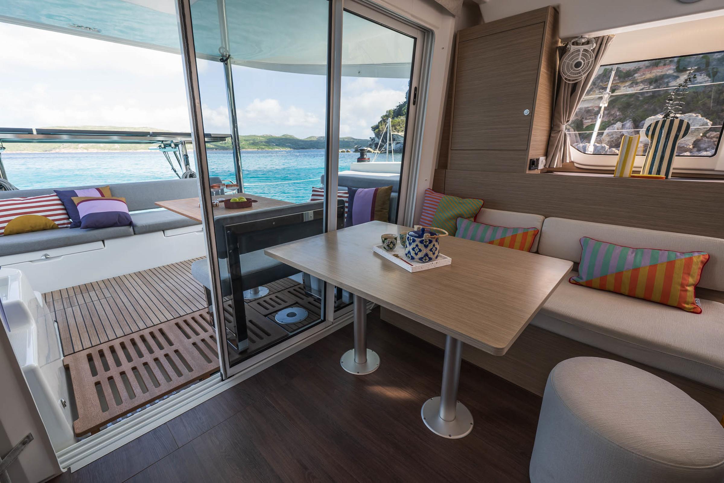 Interior of 2025 Lagoon 38 catamaran with colorful cushions and ocean view.