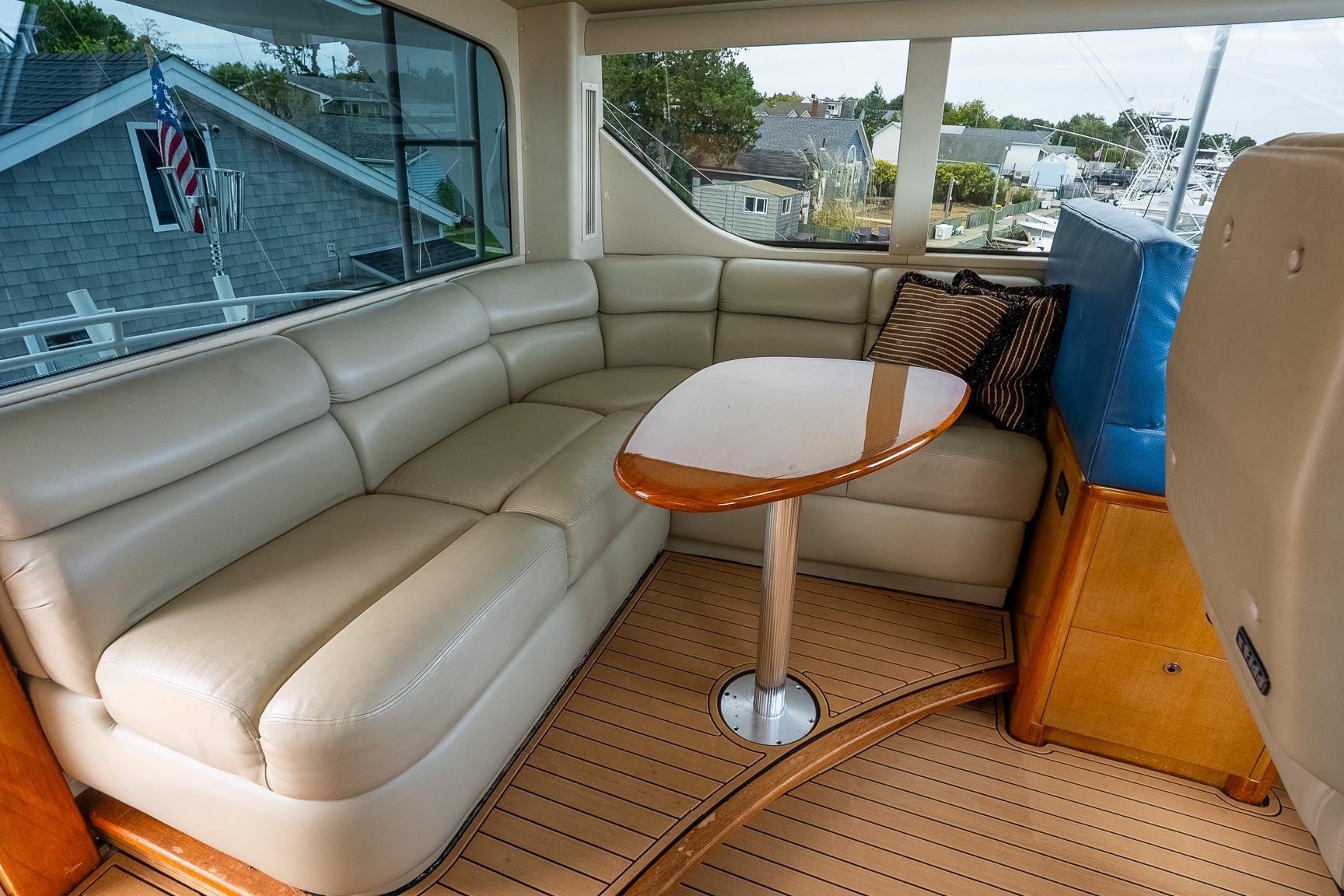 Luxurious interior of 2002 Viking 61 Enclosed Bridge yacht with leather seating and wooden table.