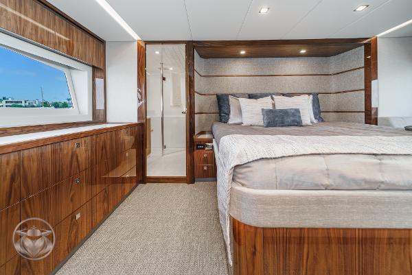 Luxurious bedroom interior of 2025 Riviera 645 SUV yacht with wood finishes and large bed.