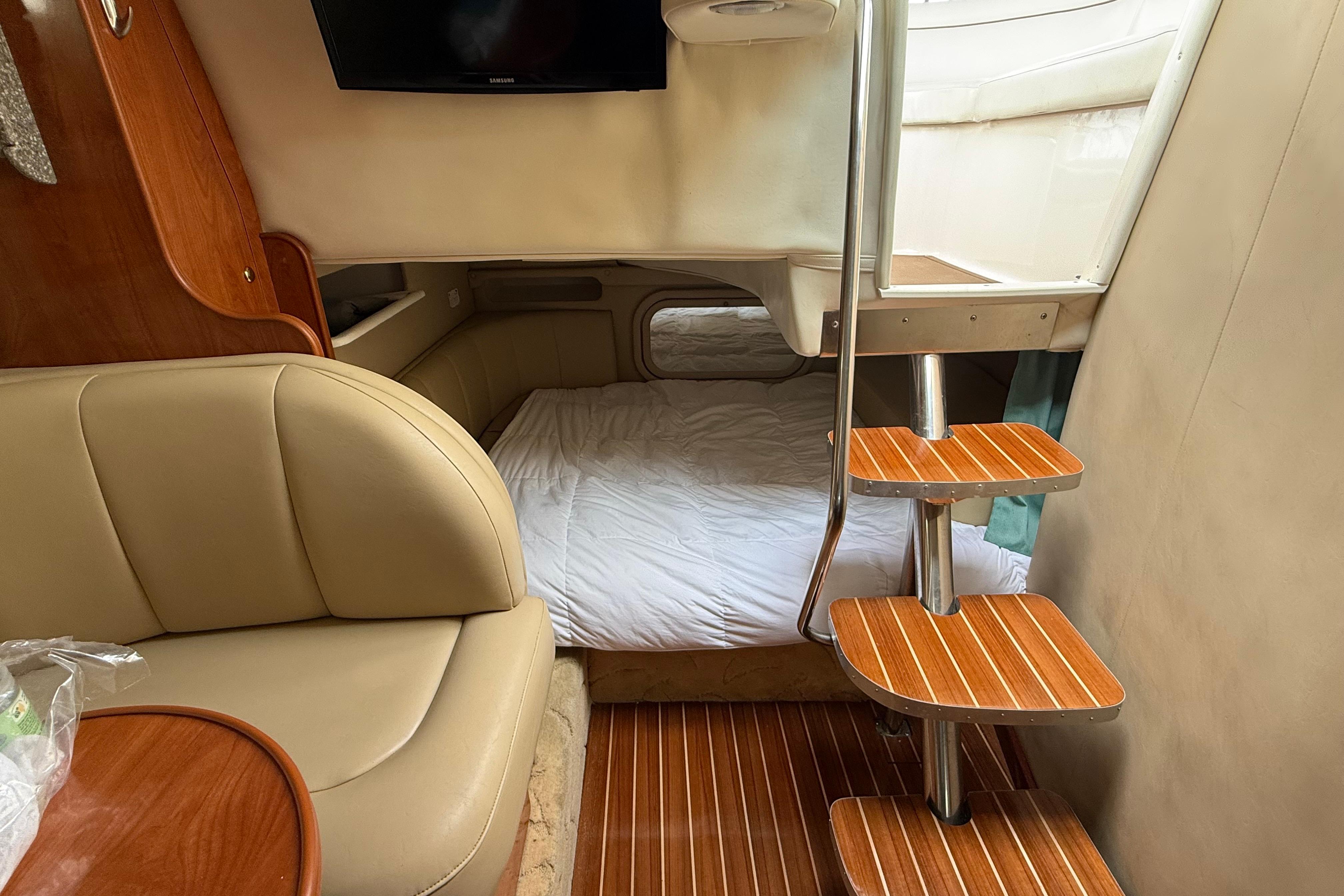 Interior of 2004 Rinker 342 boat with cozy seating, bed, and wooden stairs.