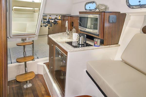 Manufacturer Provided Image: 2021 Pursuit OS 325 Offshore boat interior with kitchenette and seating area.