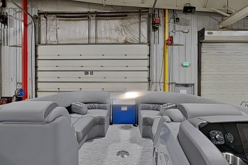 2026 Bennington 23 LXS Swingback interior with gray seating in a warehouse setting.