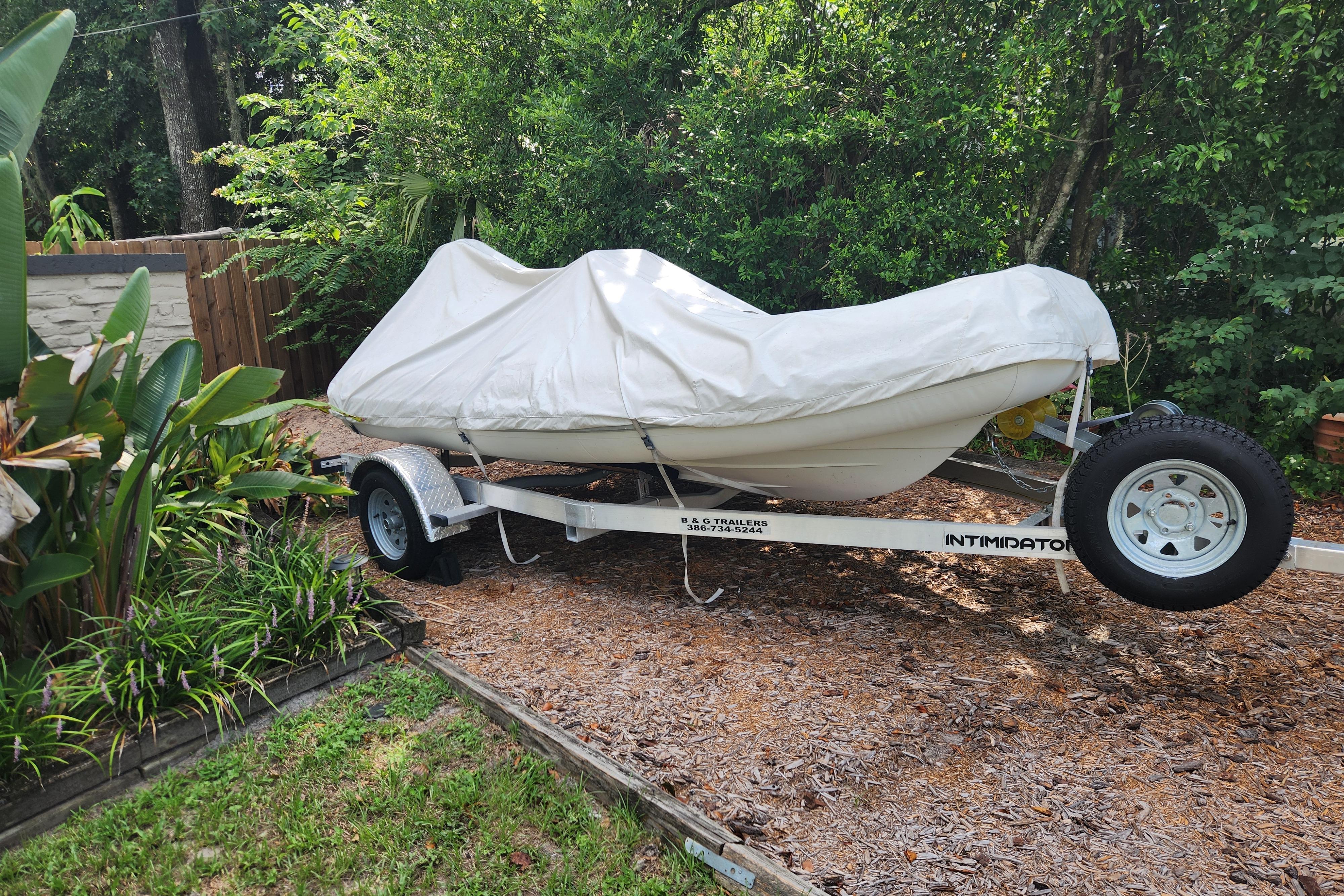 Covered 2019 Novurania DL 400 boat on trailer in garden setting.