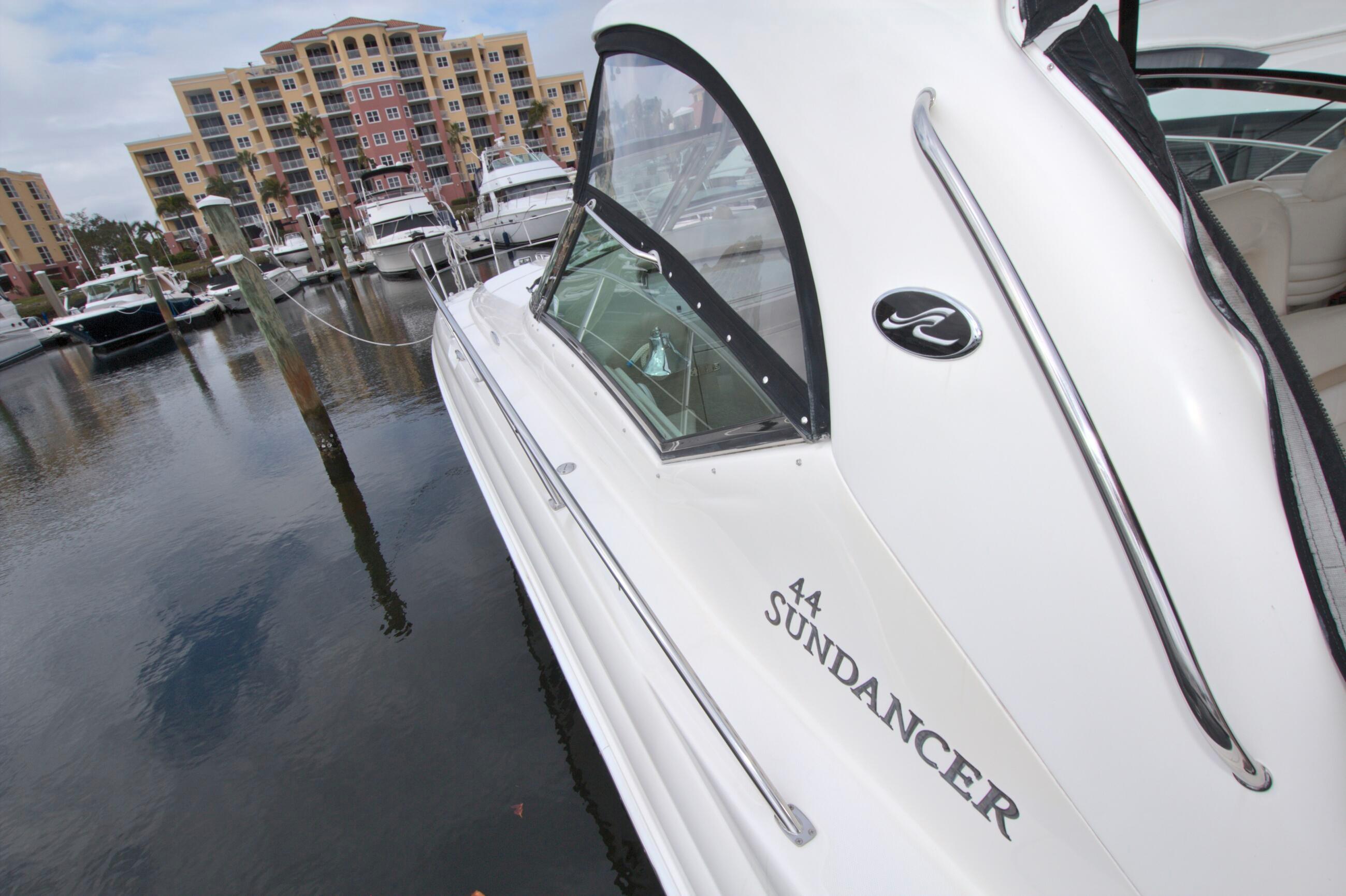 2009 Sea Ray 44 Sundancer yacht docked at marina with waterfront buildings.