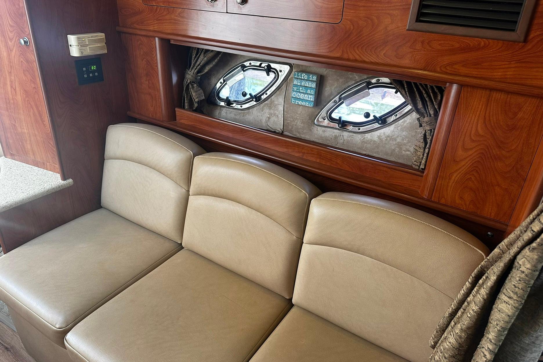 Interior of 2012 Rinker 310 Express Cruiser LE with beige seating and wood accents.