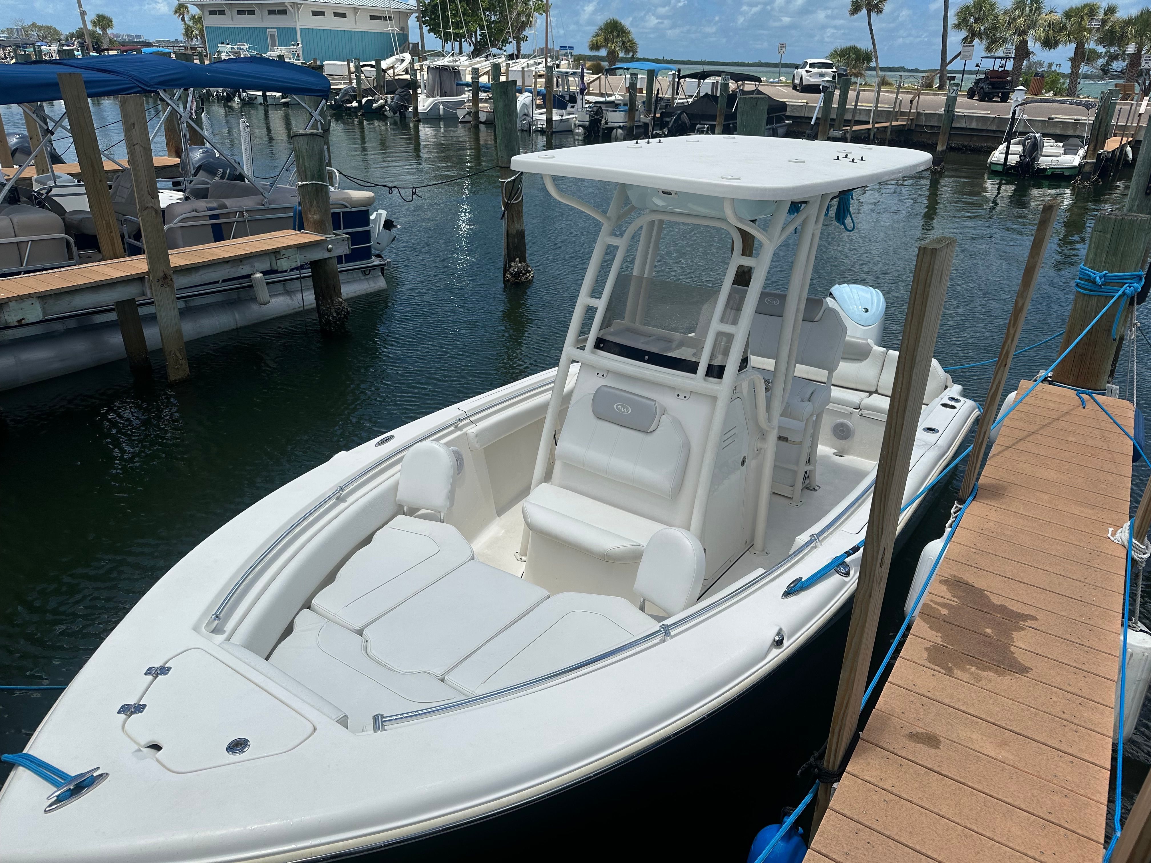 A white boat is docked at a marina, surrounded by other boats.