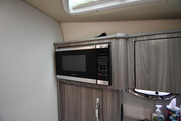 Modern kitchen area in 2021 Regal 35 Sport Coupe with microwave and wood cabinetry.