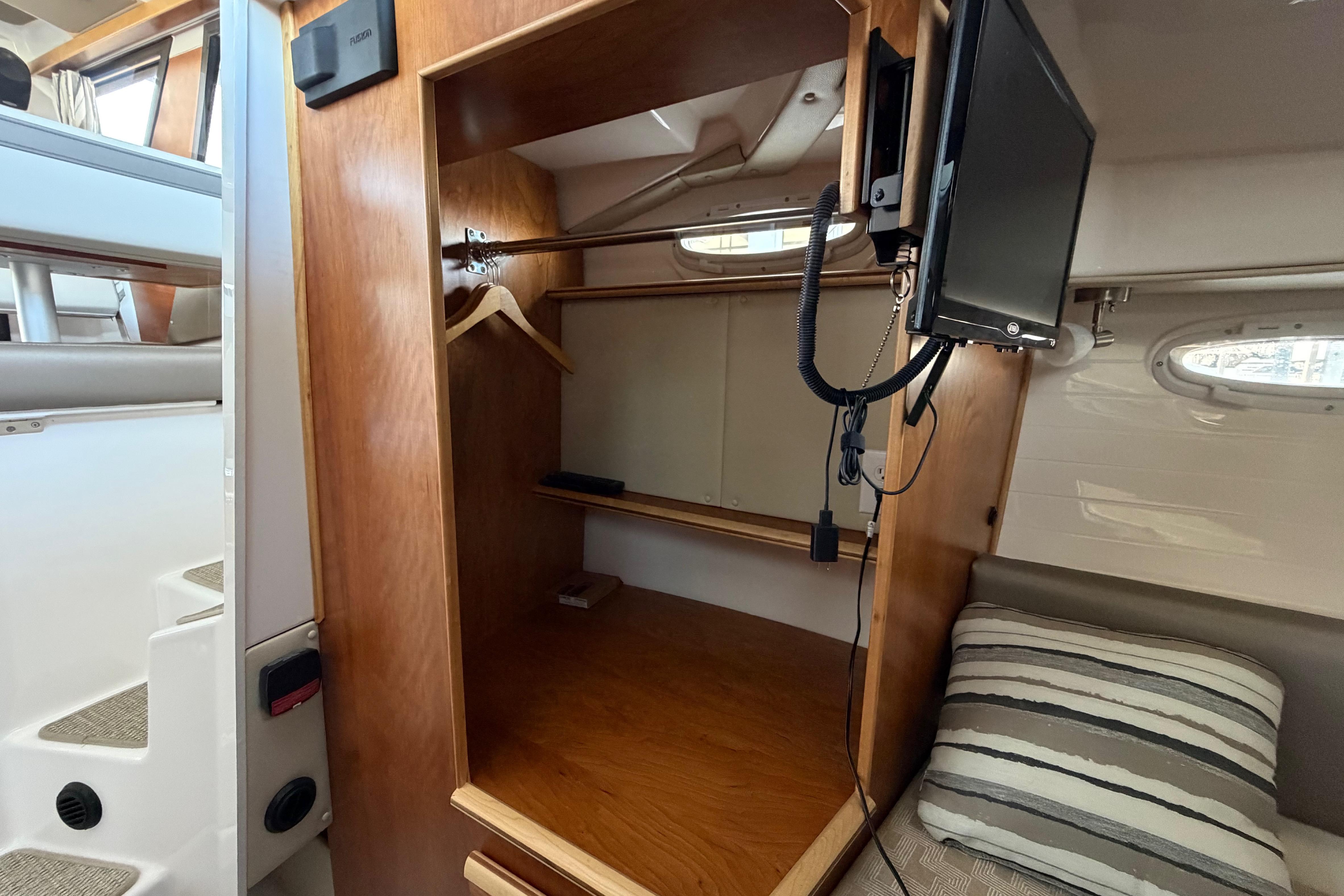 2023 Cutwater C-288 Coupe interior with wooden closet, TV, and striped cushion.
