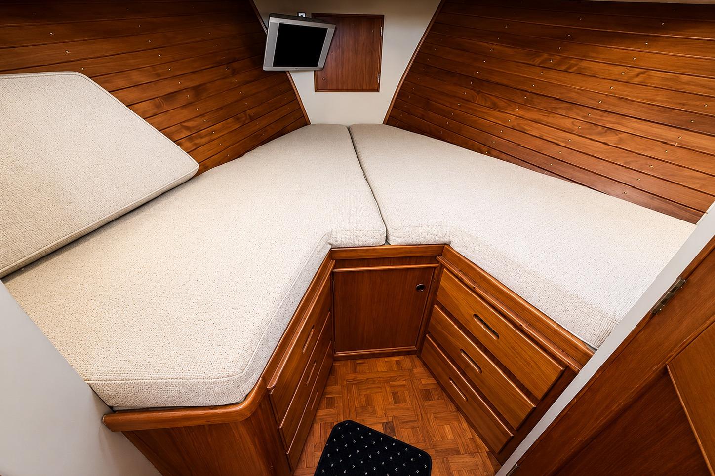 Cozy cabin interior of 1989 Grand Banks 42 Classic yacht with wooden paneling and bedding.
