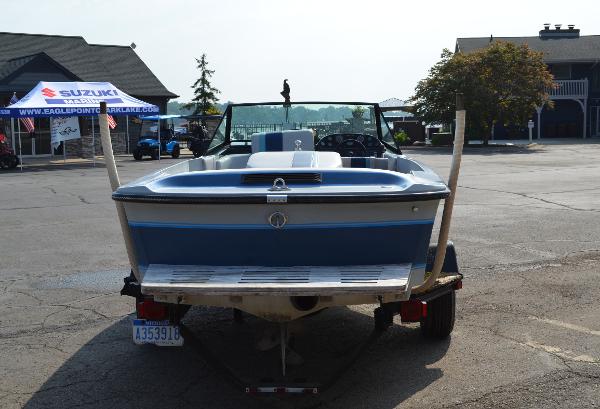 1989 Correct Craft Ski Nautique boat on trailer, parked in a lot with tents and buildings.