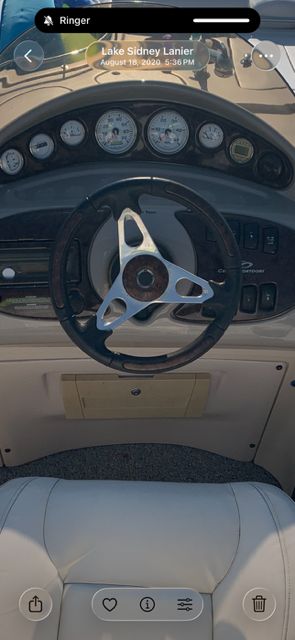 The image shows a boat's helm with multiple gauges and a leather-wrapped steering wheel.