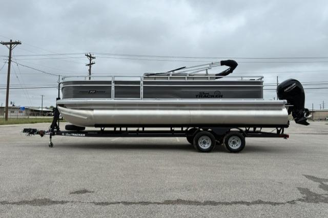 2026 Sun Tracker Fishin' Barge 22 DLX pontoon boat on trailer, parked outdoors.