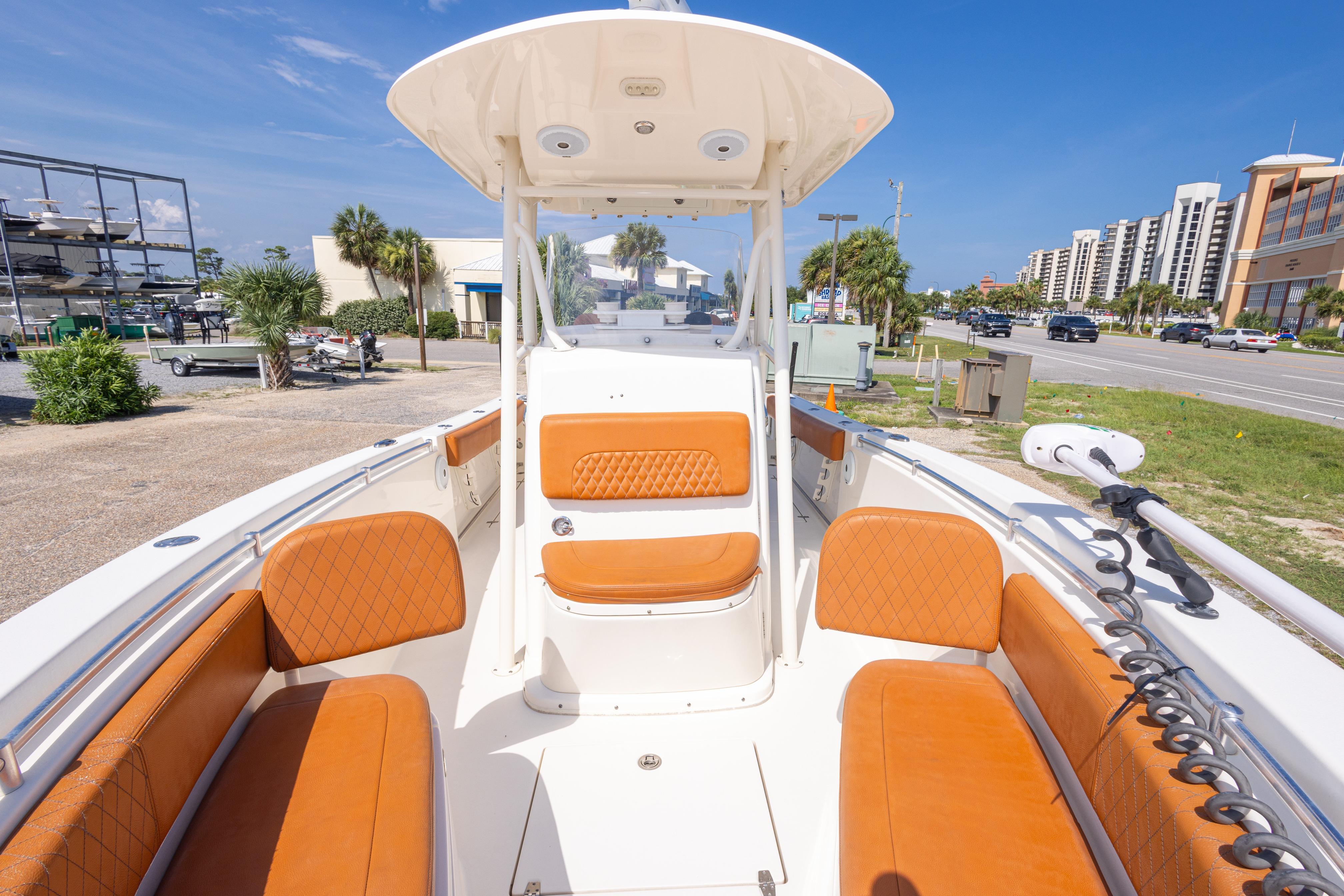 2017 Cobia 261 Center Console boat with orange seating, parked near a coastal road.