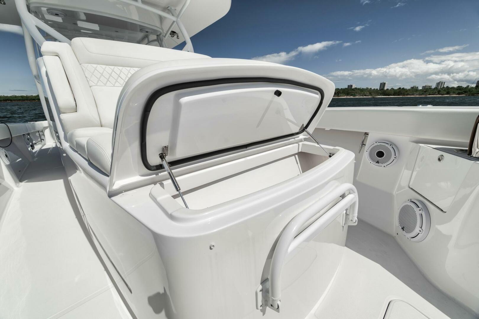 2023 Jupiter 40 boat interior with open storage compartment, white seating, and ocean view.