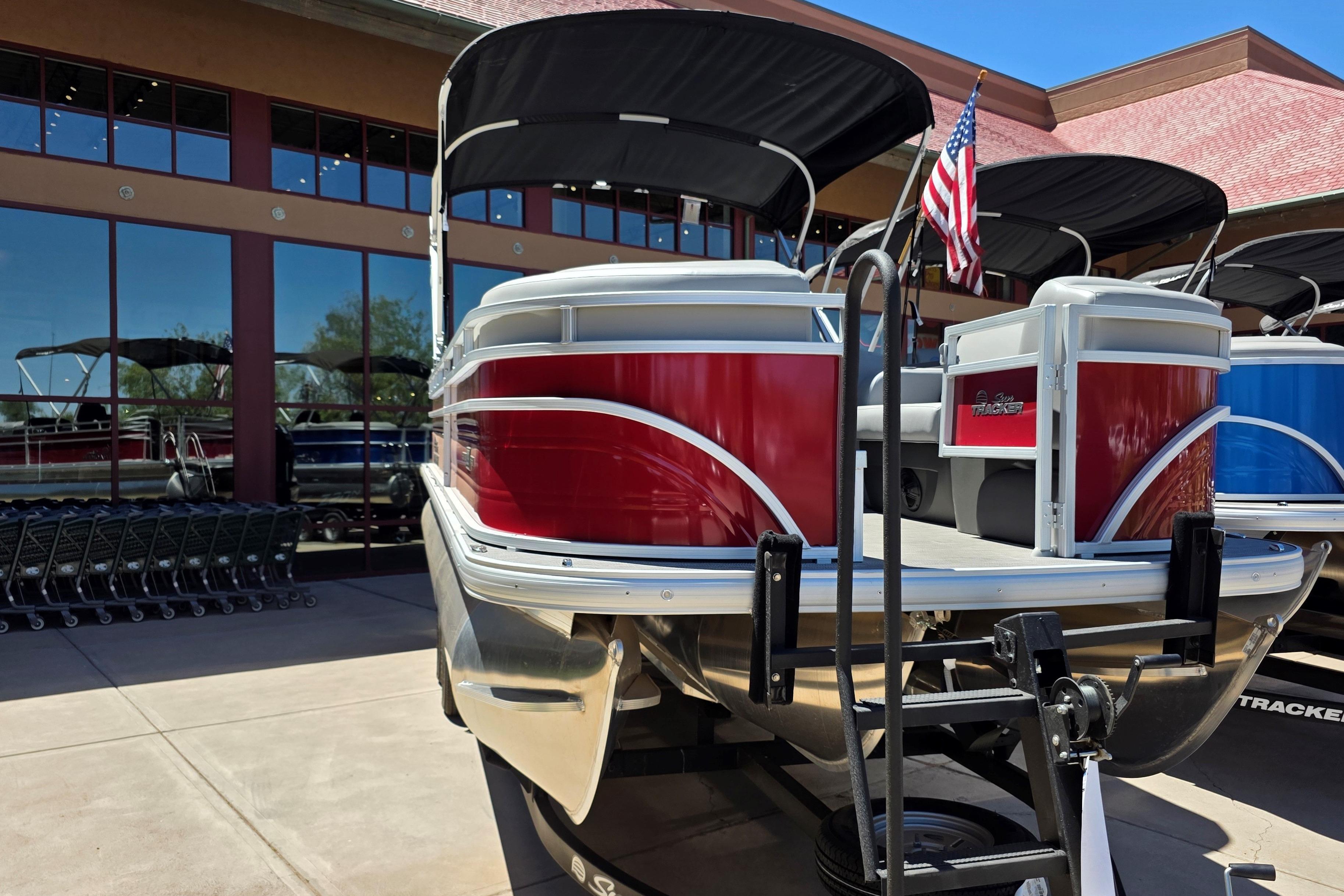 2026 Sun Tracker SportFish 22 XP3 pontoon boat with red exterior, displayed outdoors.