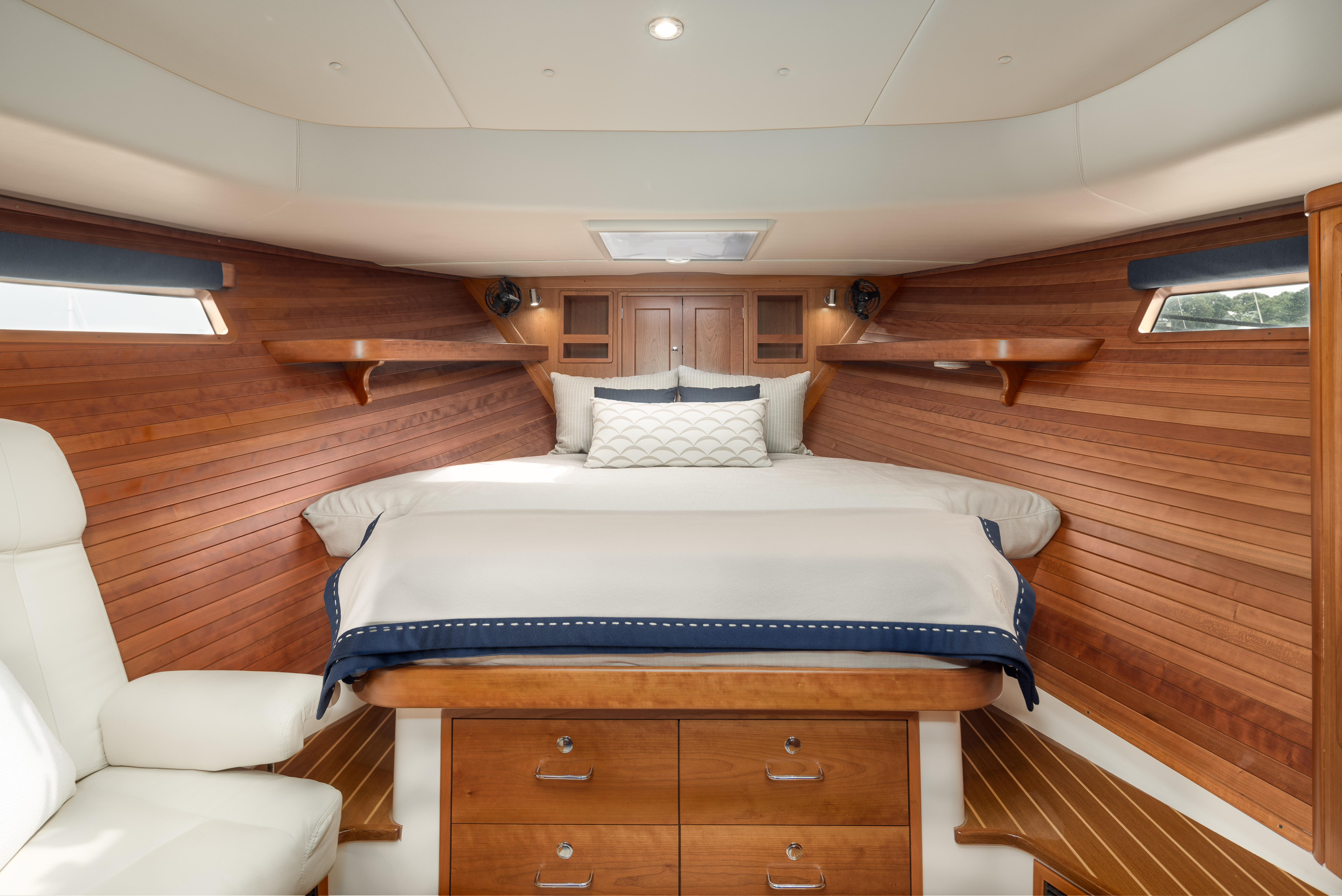 Luxurious cabin interior of 2020 MJM 53z yacht with wooden paneling and cozy bedding.