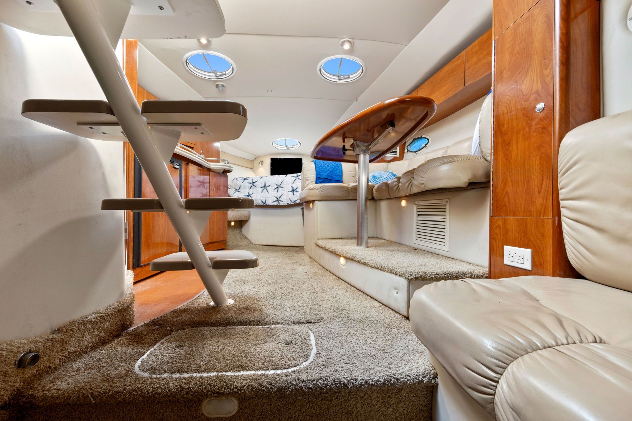 Interior of a 2007 Larson Cabrio 330 with carpeted floor, leather seating, and portholes.