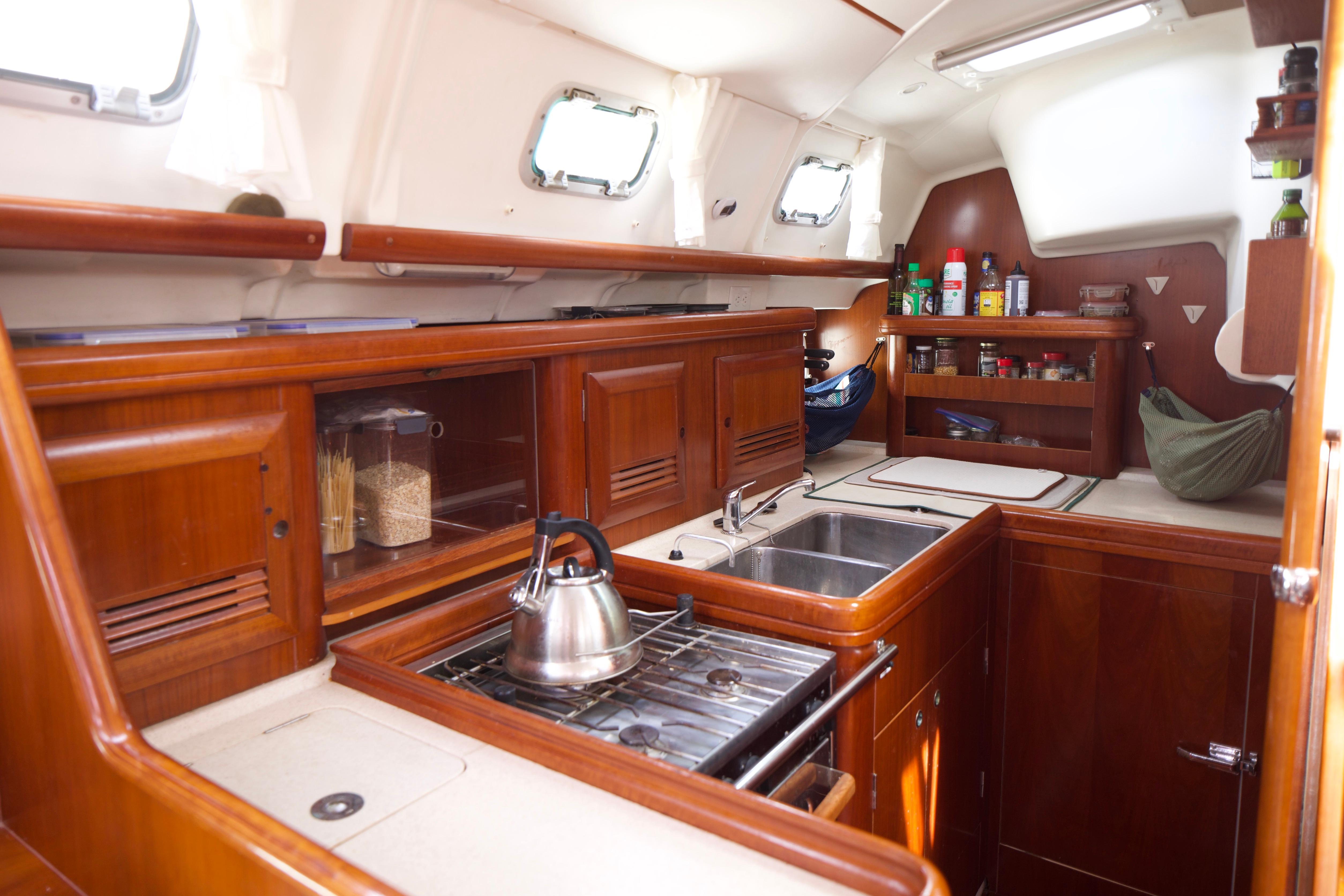 Interior of 2005 Beneteau 423 yacht kitchen with wooden cabinetry and stainless steel sink.