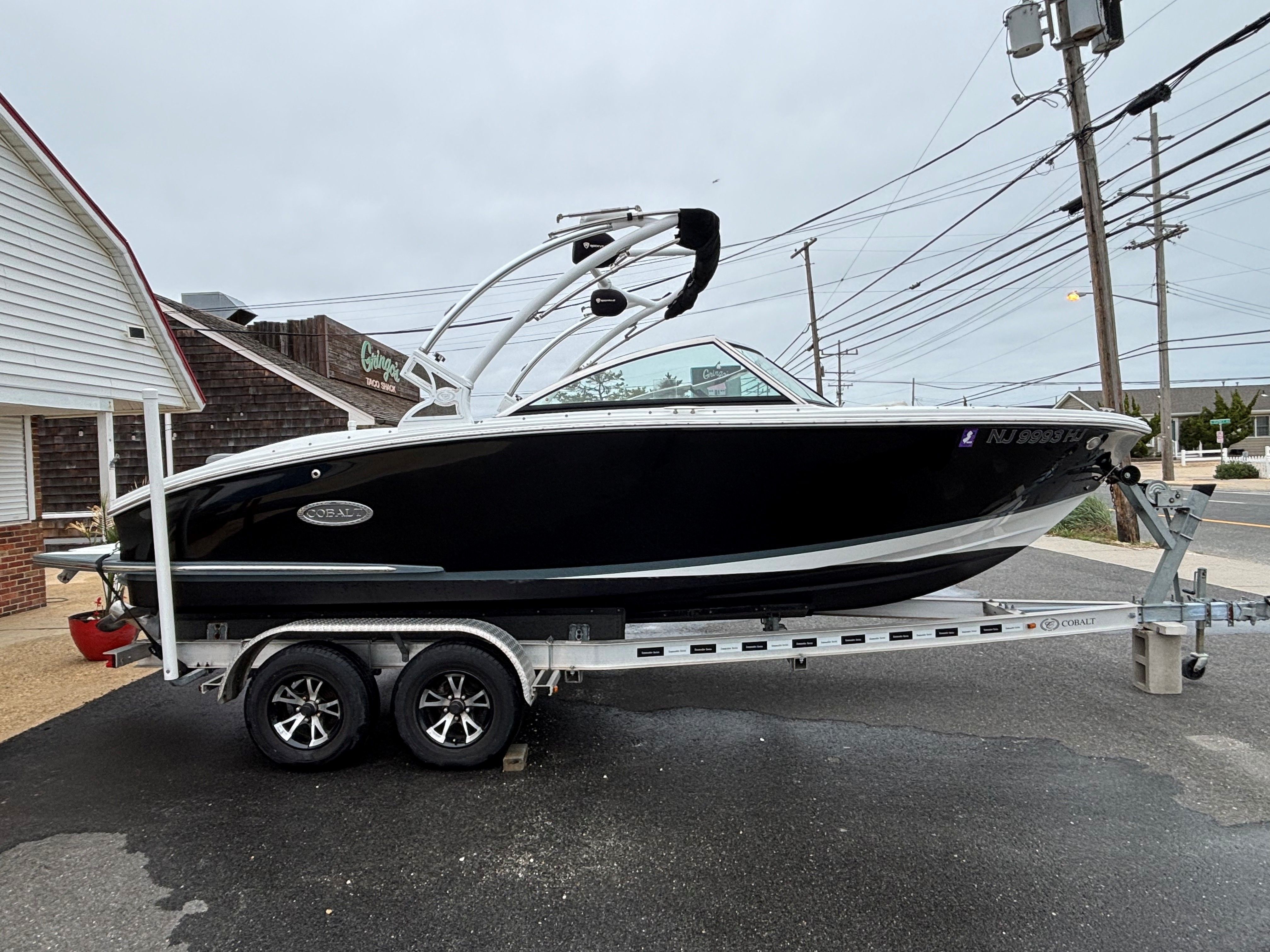 A black 2019 Cobalt CS22 boat on a trailer next to a building.