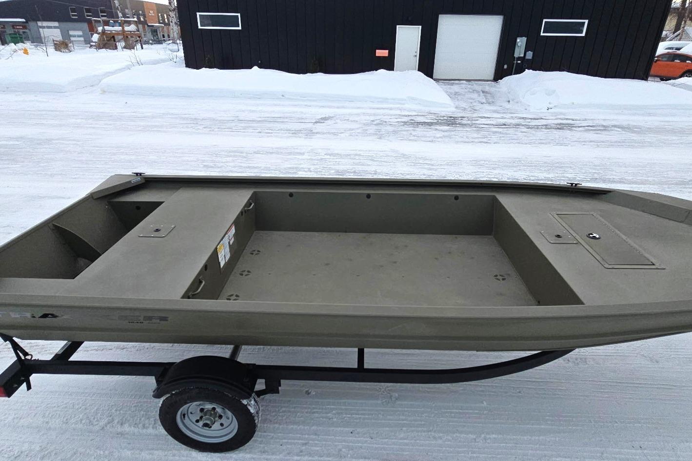 2025 Tracker Grizzly 1648 Jon boat on trailer, parked on snowy ground.