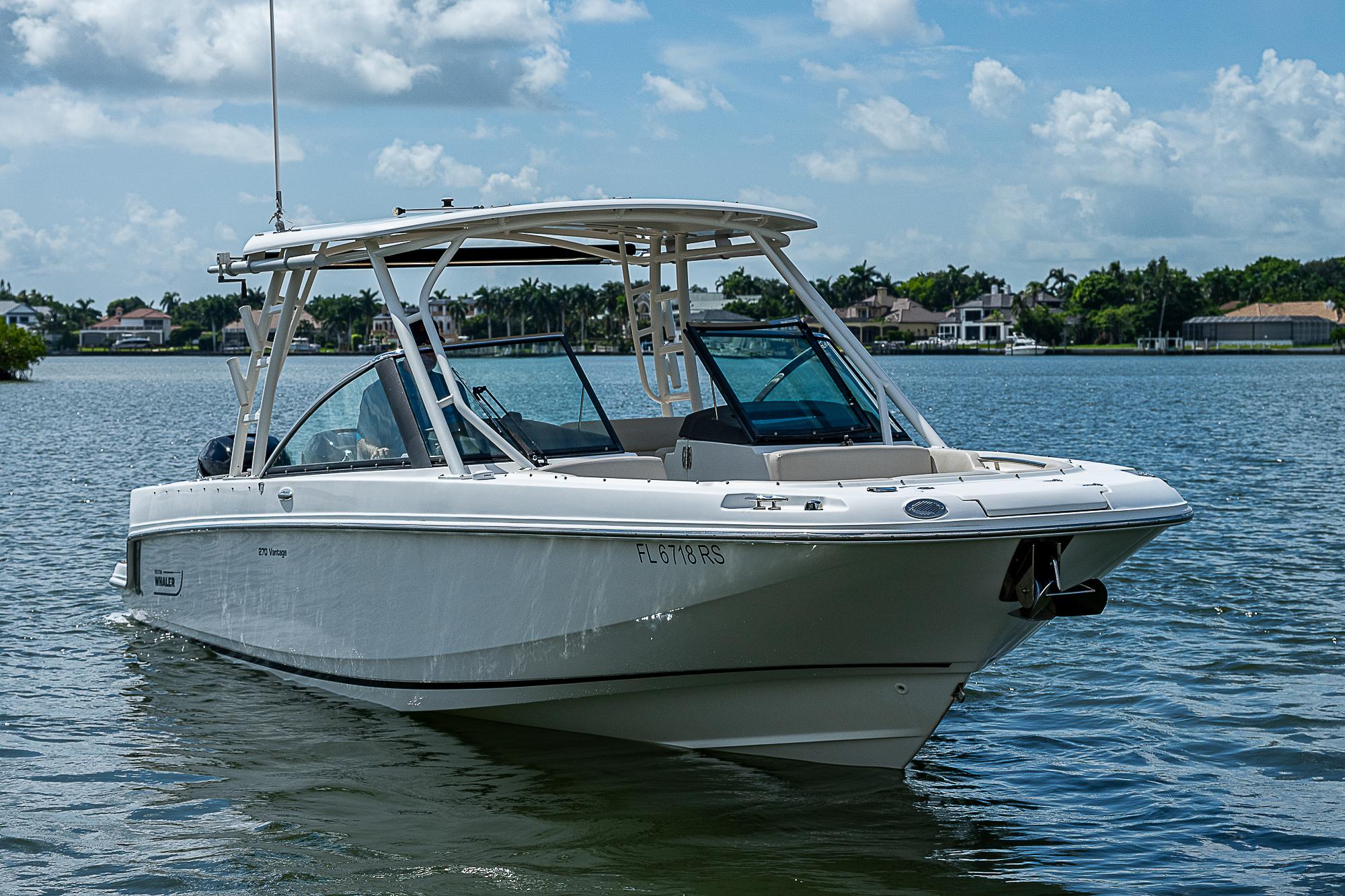 2018 Boston Whaler 270 Vantage boat on a calm lake under a blue sky.