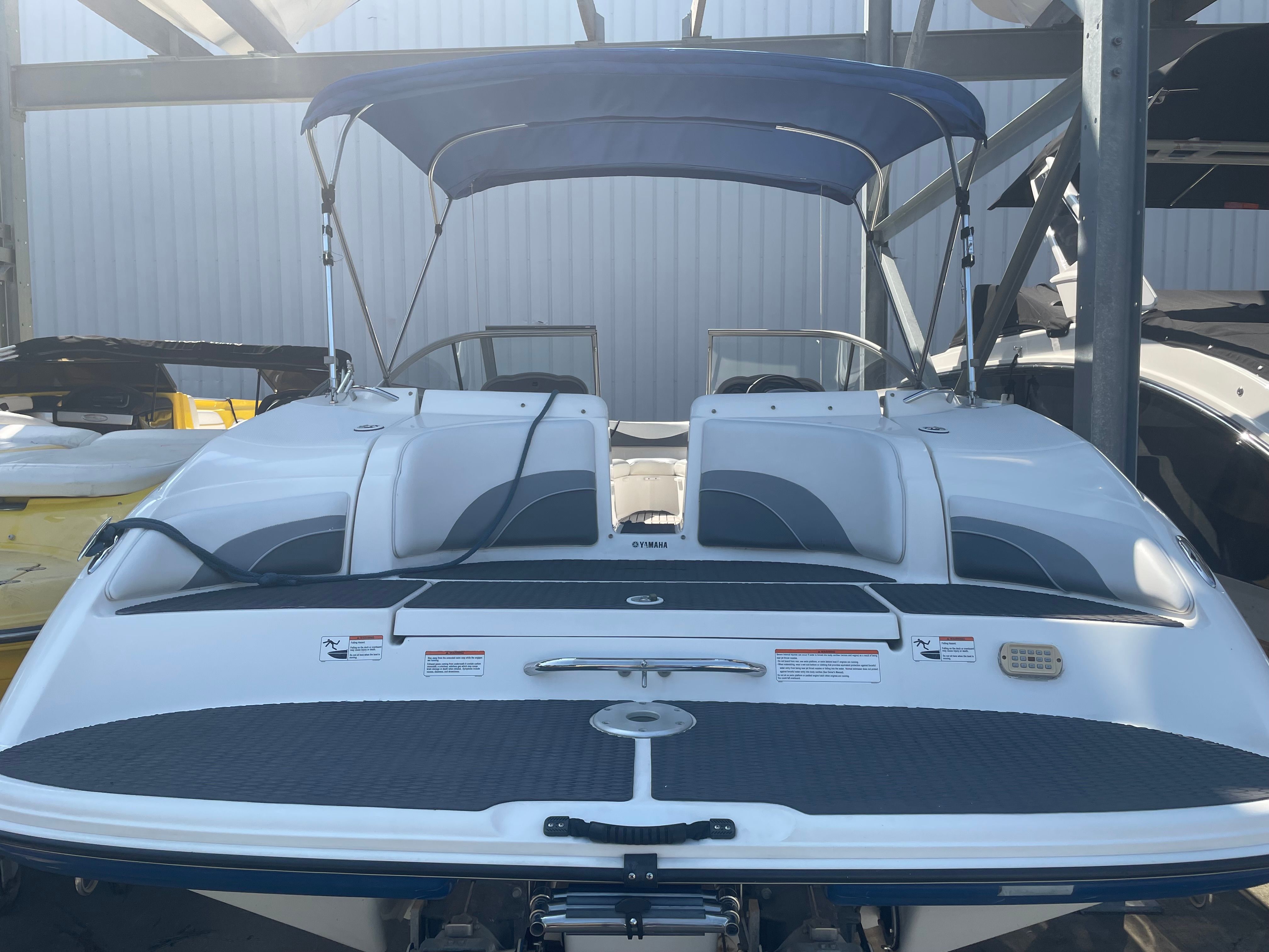A 2006 Yamaha SX230 boat with a blue sunshade, parked in a storage facility.
