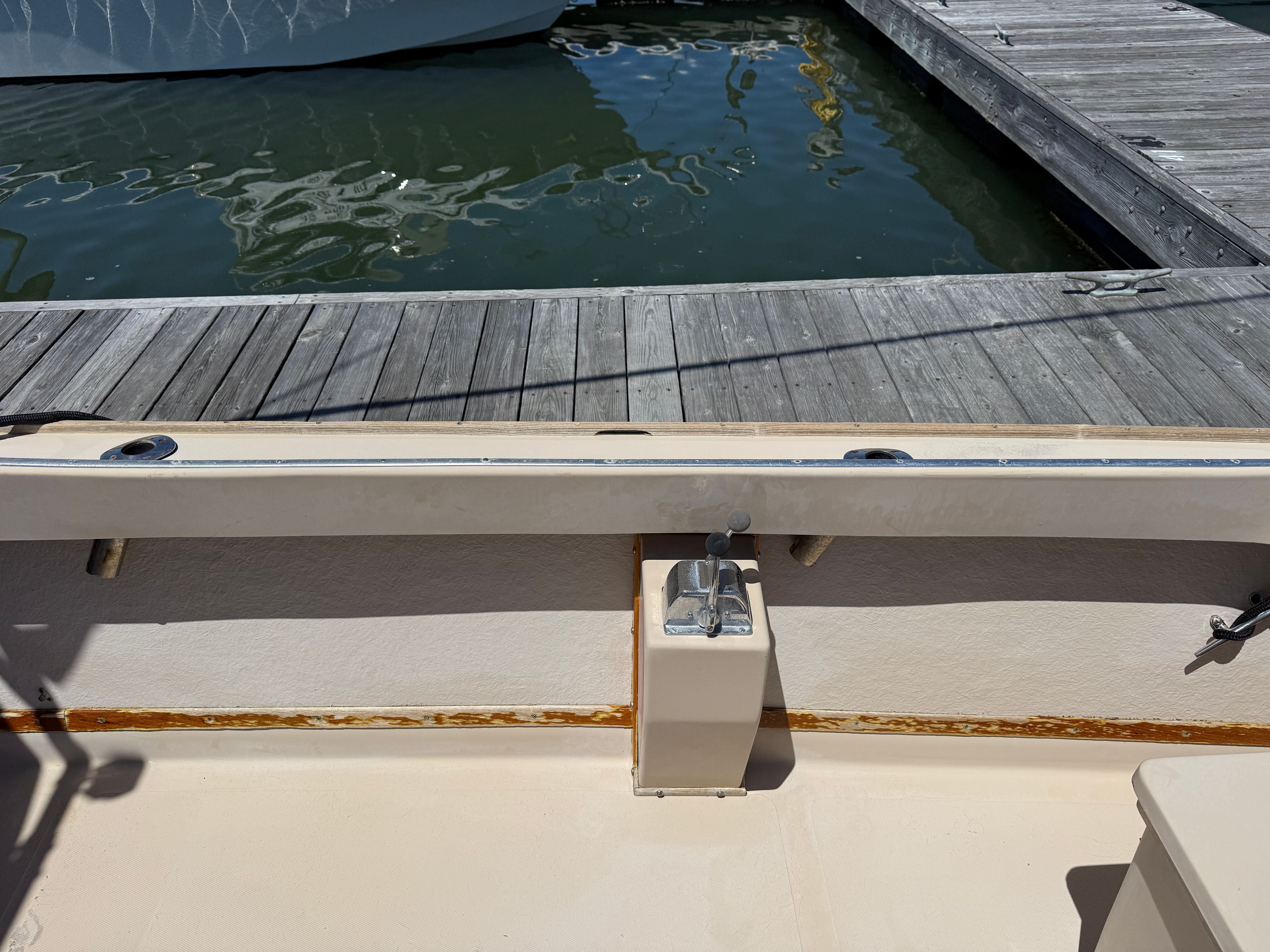 A boat at the dock with wooden details and water in the background.