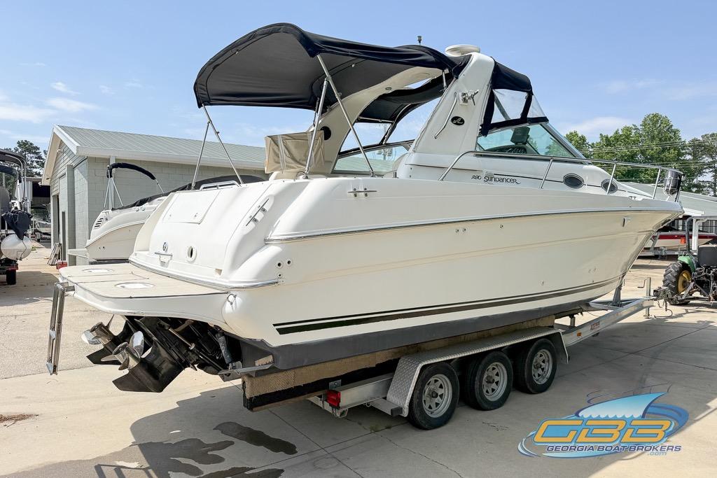 1999 Sea Ray 290 Sundancer boat on trailer at marina, featuring sleek design and canopy.