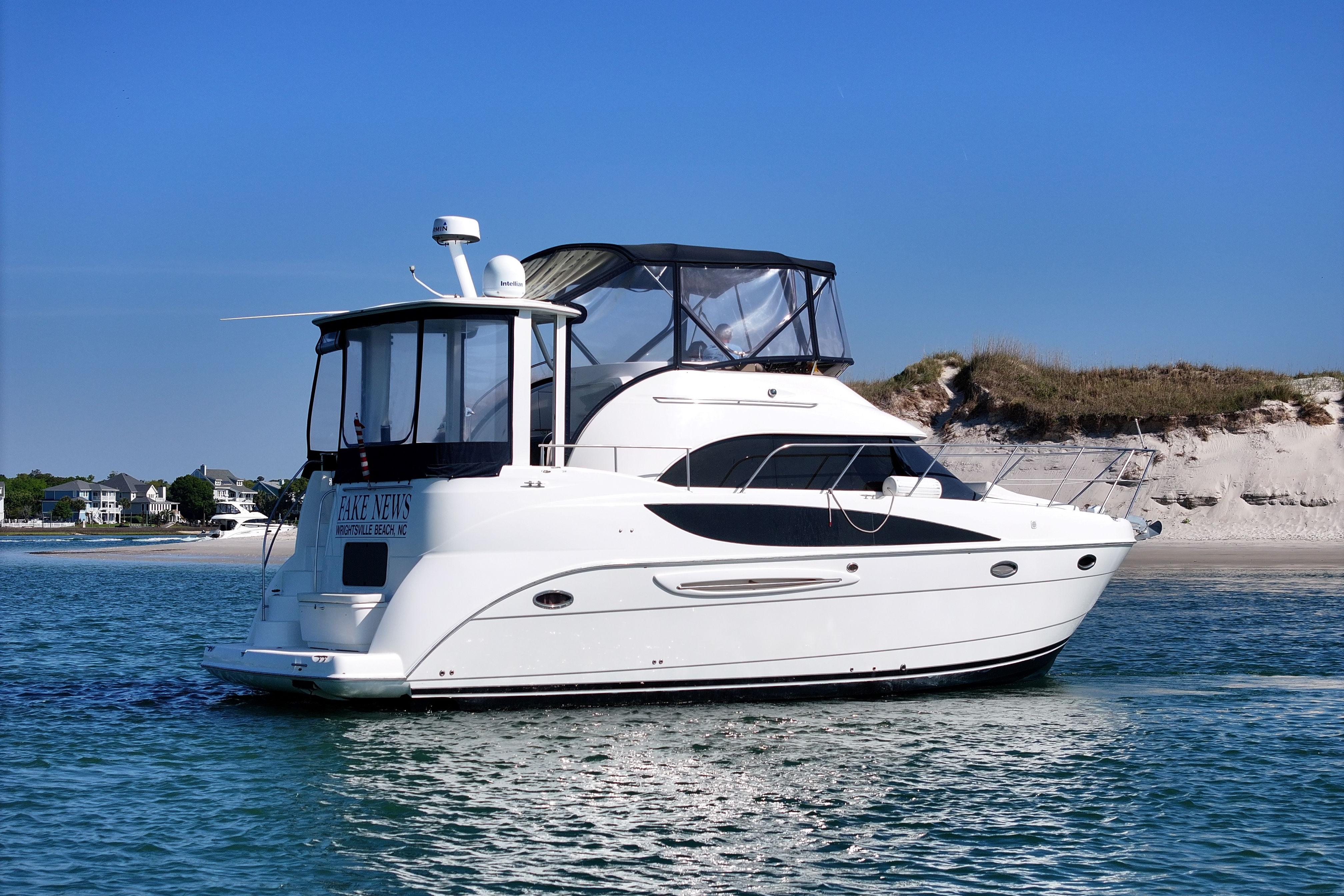 2005 Meridian 368 Motoryacht cruising near sandy shoreline under clear blue sky.