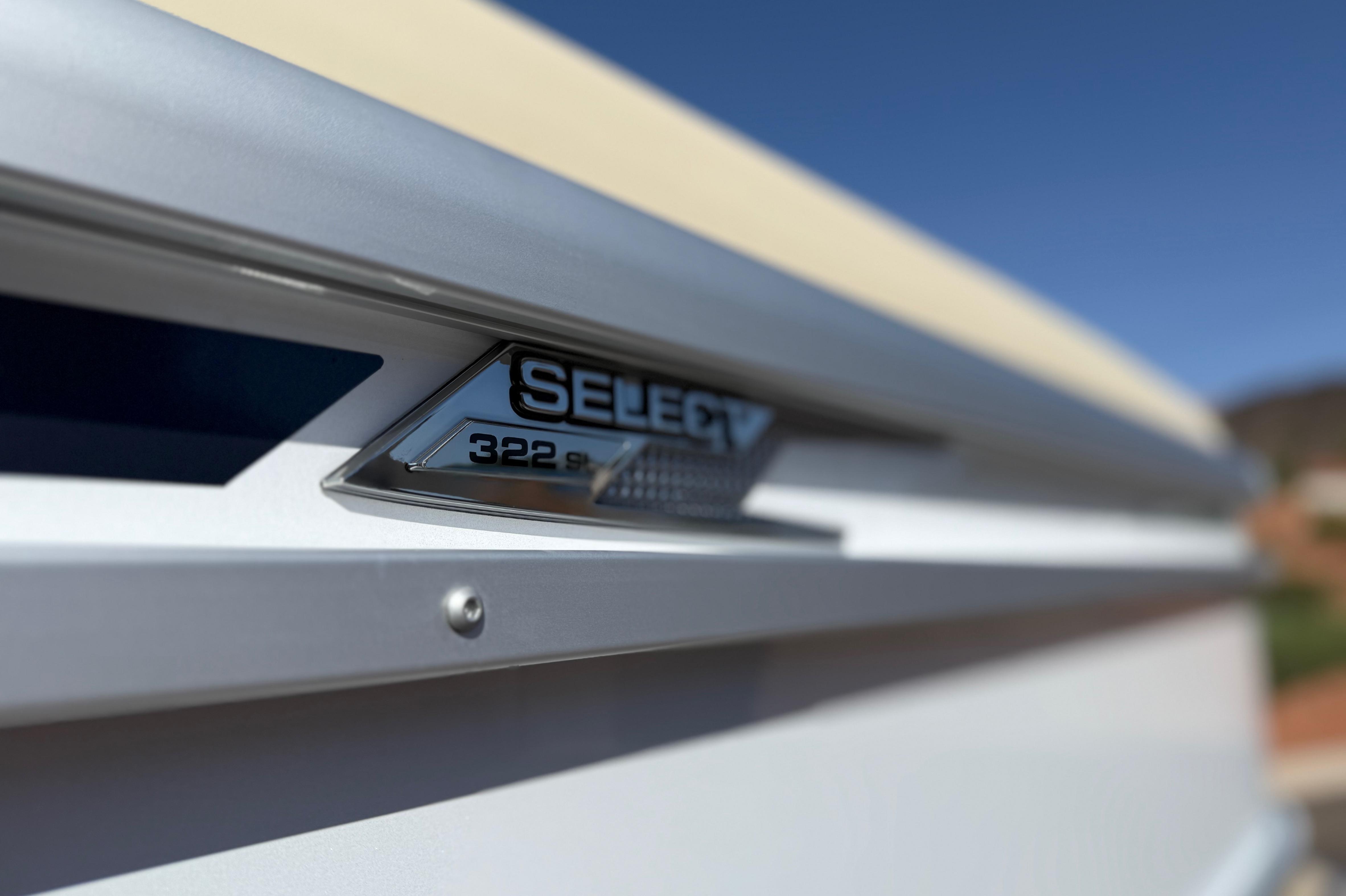 Close-up of 2026 SunCatcher Select 322SL boat emblem against a clear blue sky.