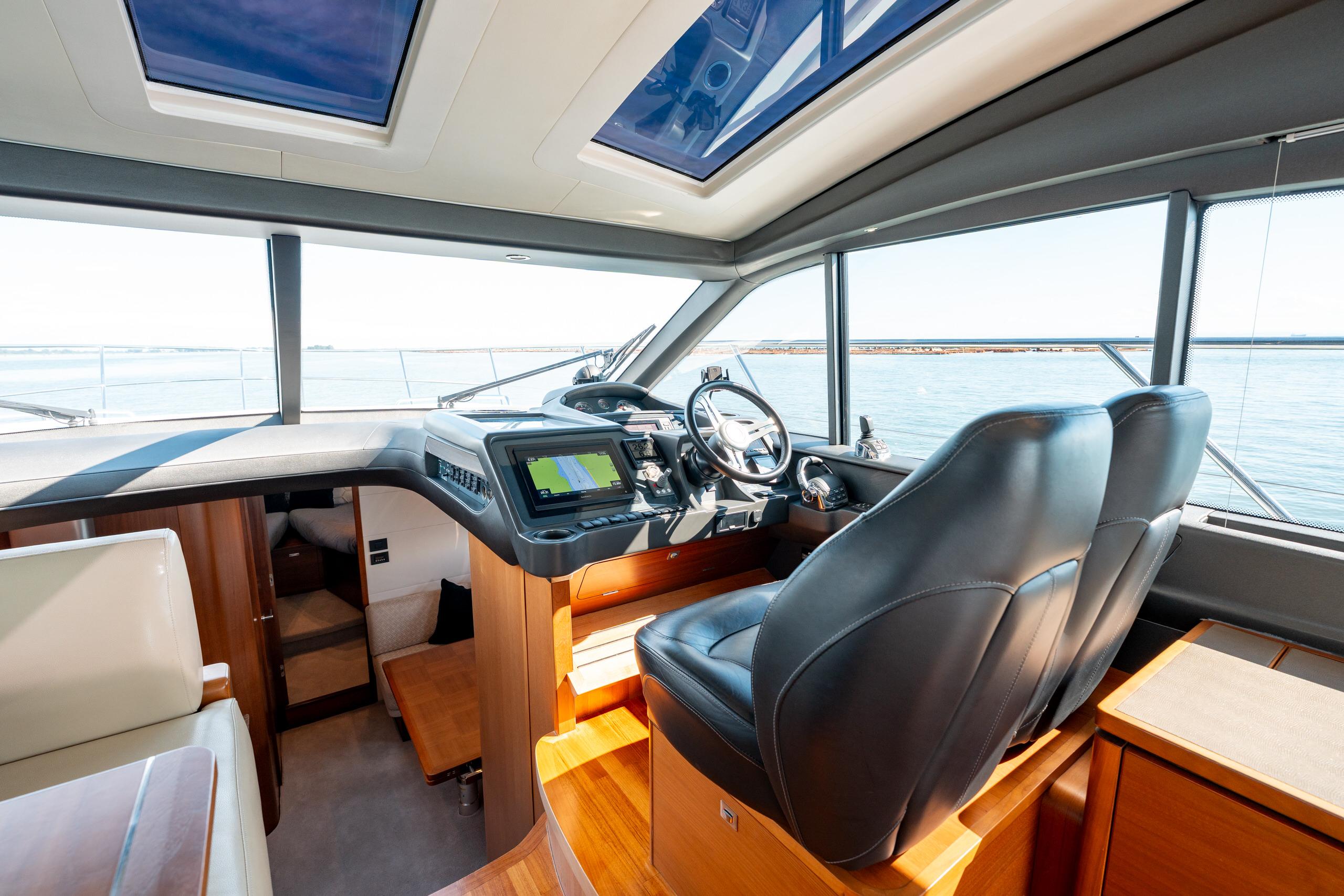 Interior of 2015 Princess V48 yacht cockpit with leather seats and navigation controls.