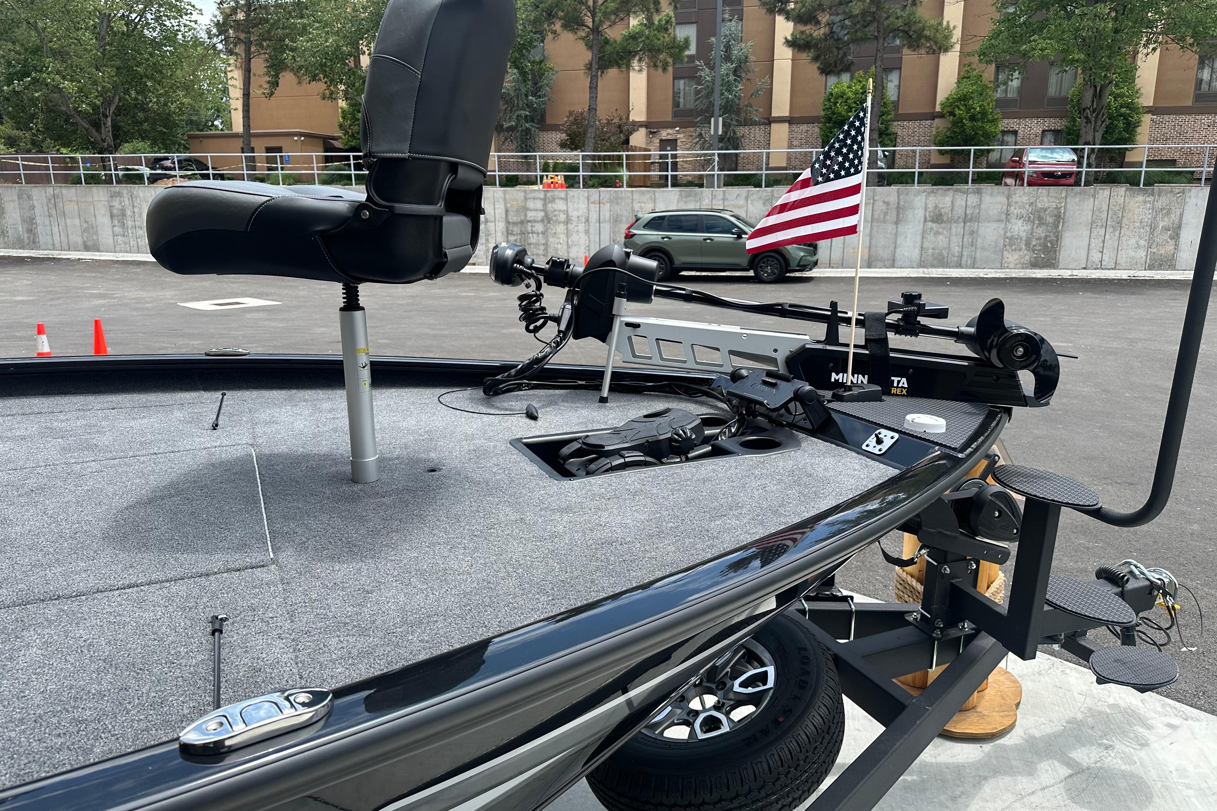 2025 Tracker Savage 215 boat with fishing seat and trolling motor, parked with American flag.
