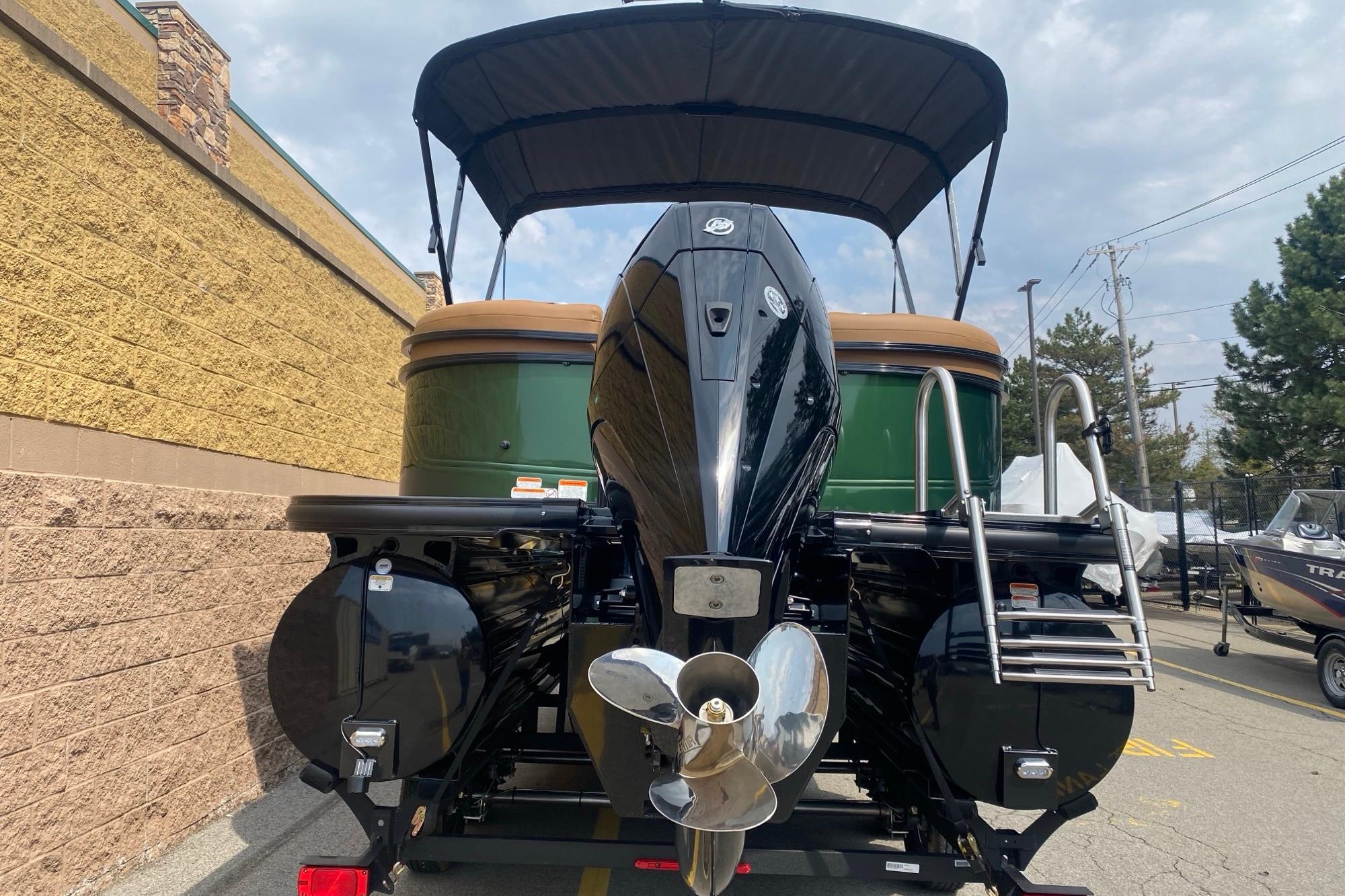 2026 Regency 230 DL boat with outboard motor and canopy, parked outdoors.