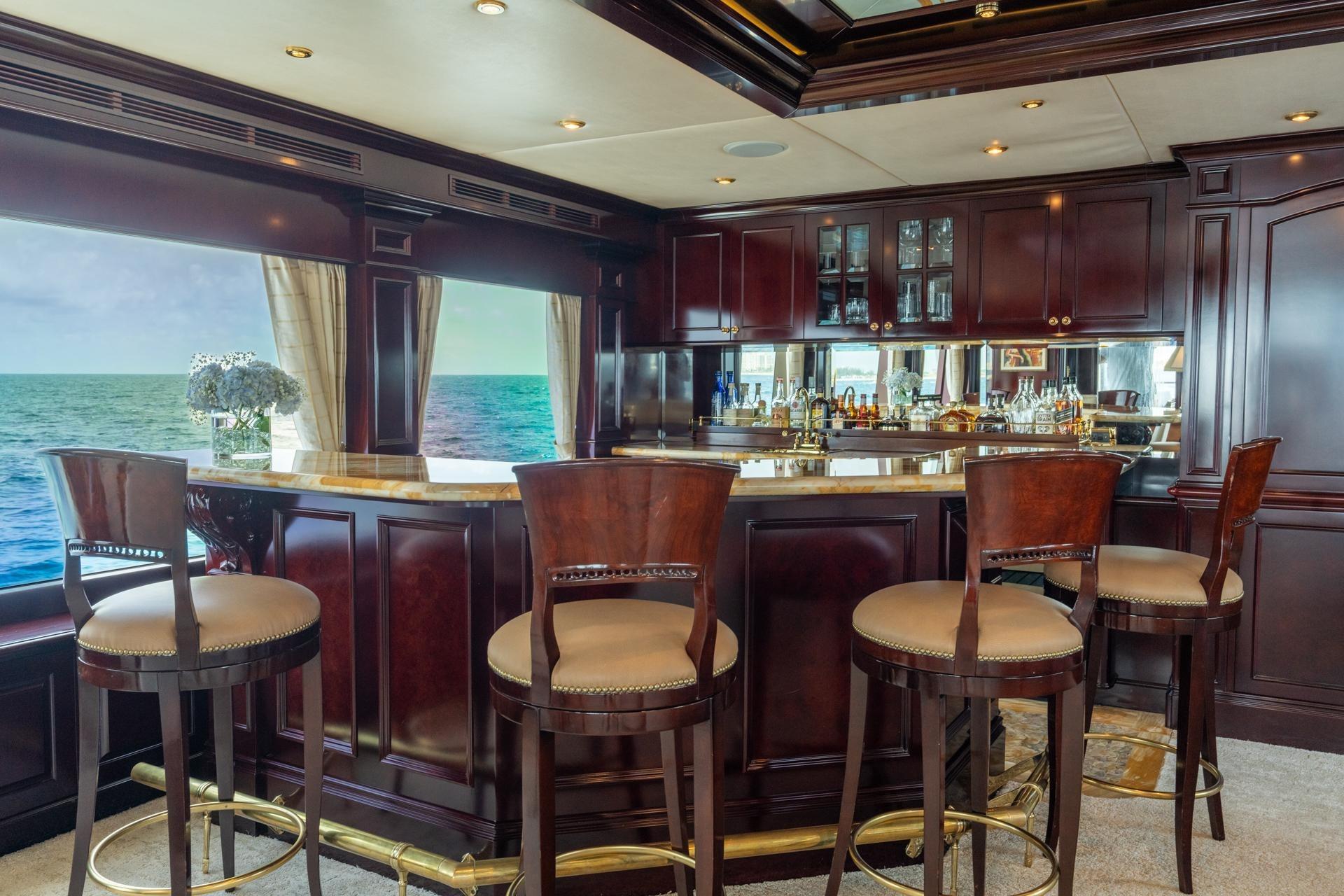 Luxurious yacht bar interior with ocean view, featuring elegant wood finishes and plush seating.