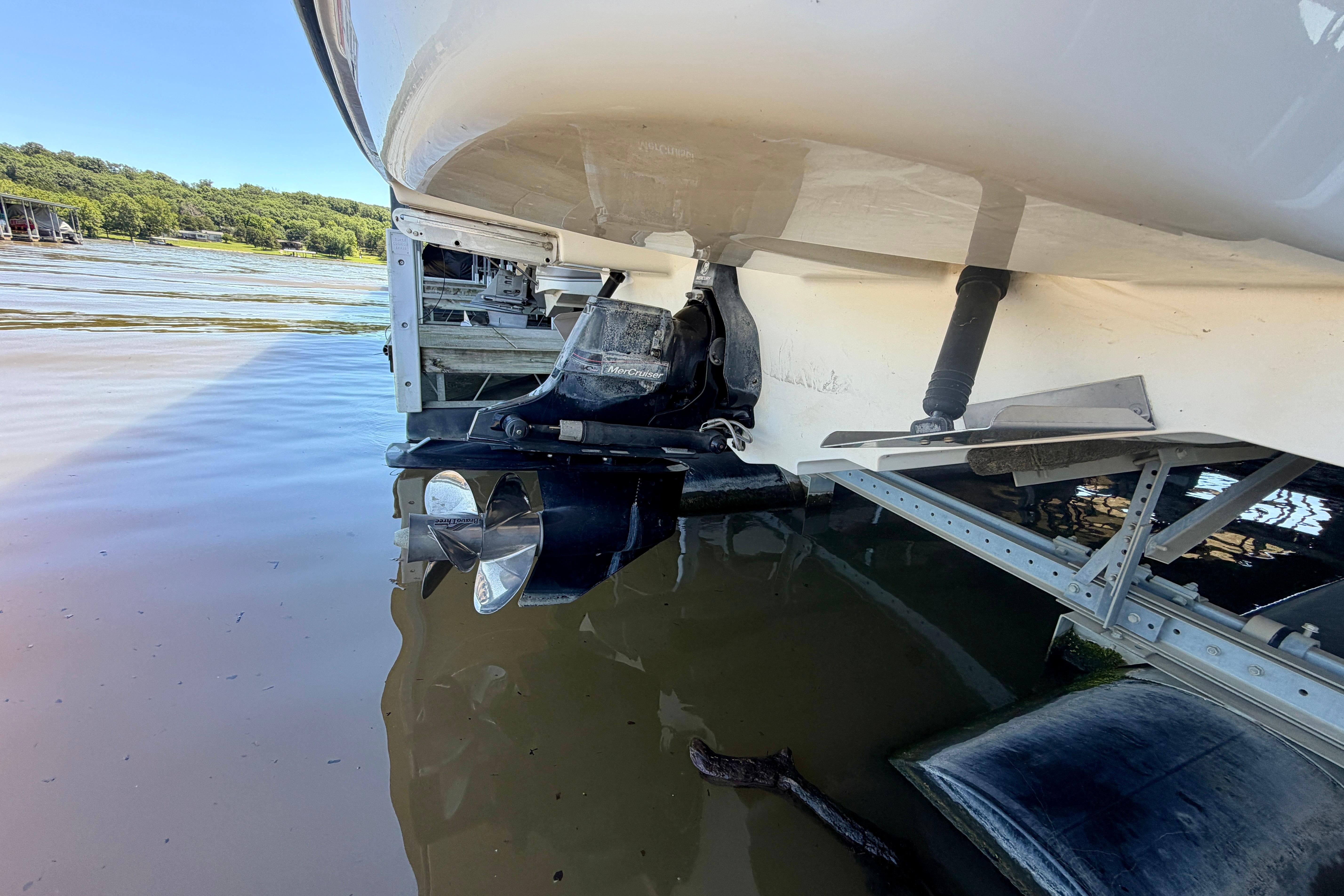 2007 Sea Ray 270 SLX boat stern with propeller in water, docked by a lake.