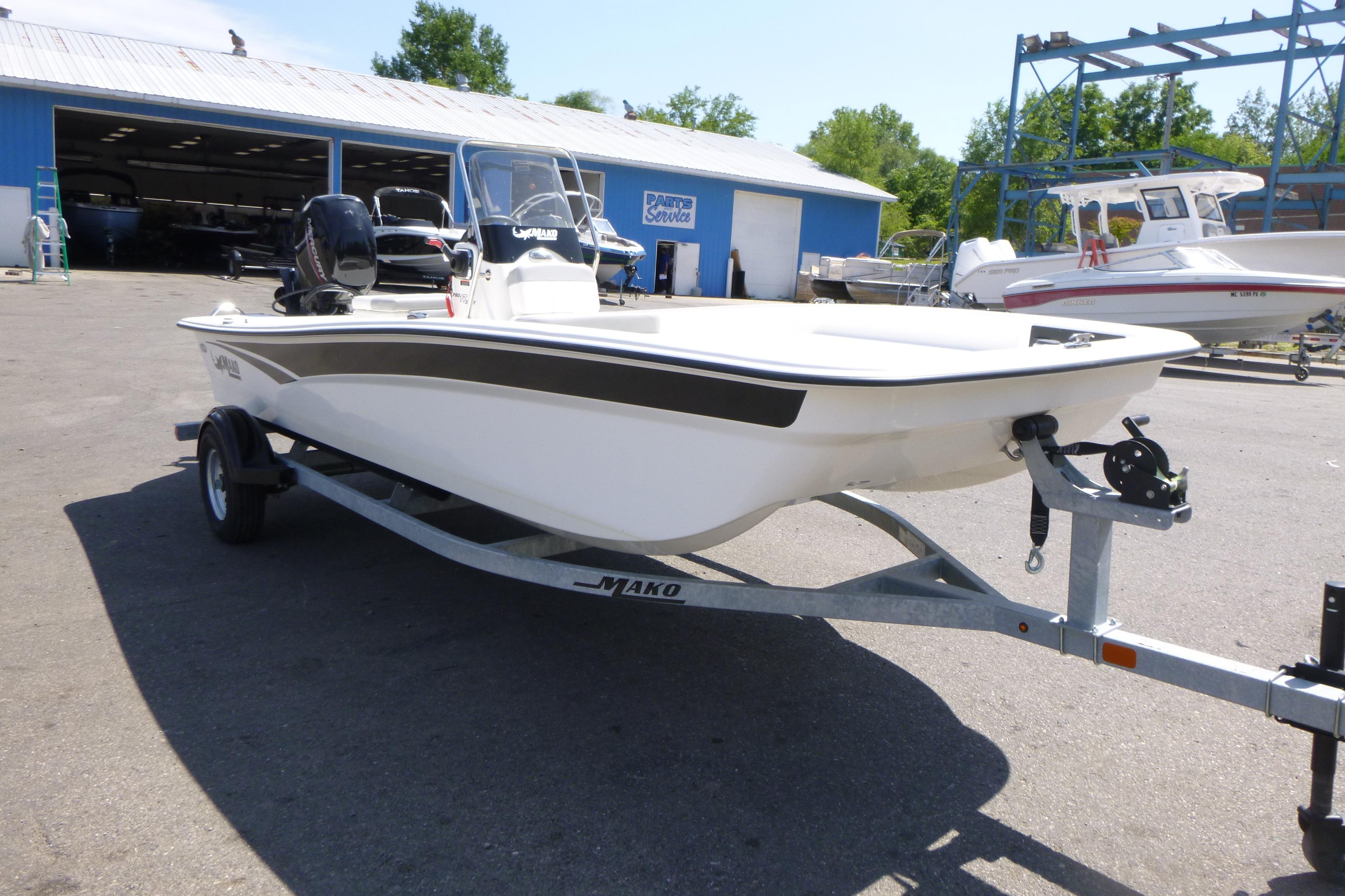 2024 Mako Pro Skiff 17 CC boat on trailer, parked outdoors near a blue building.