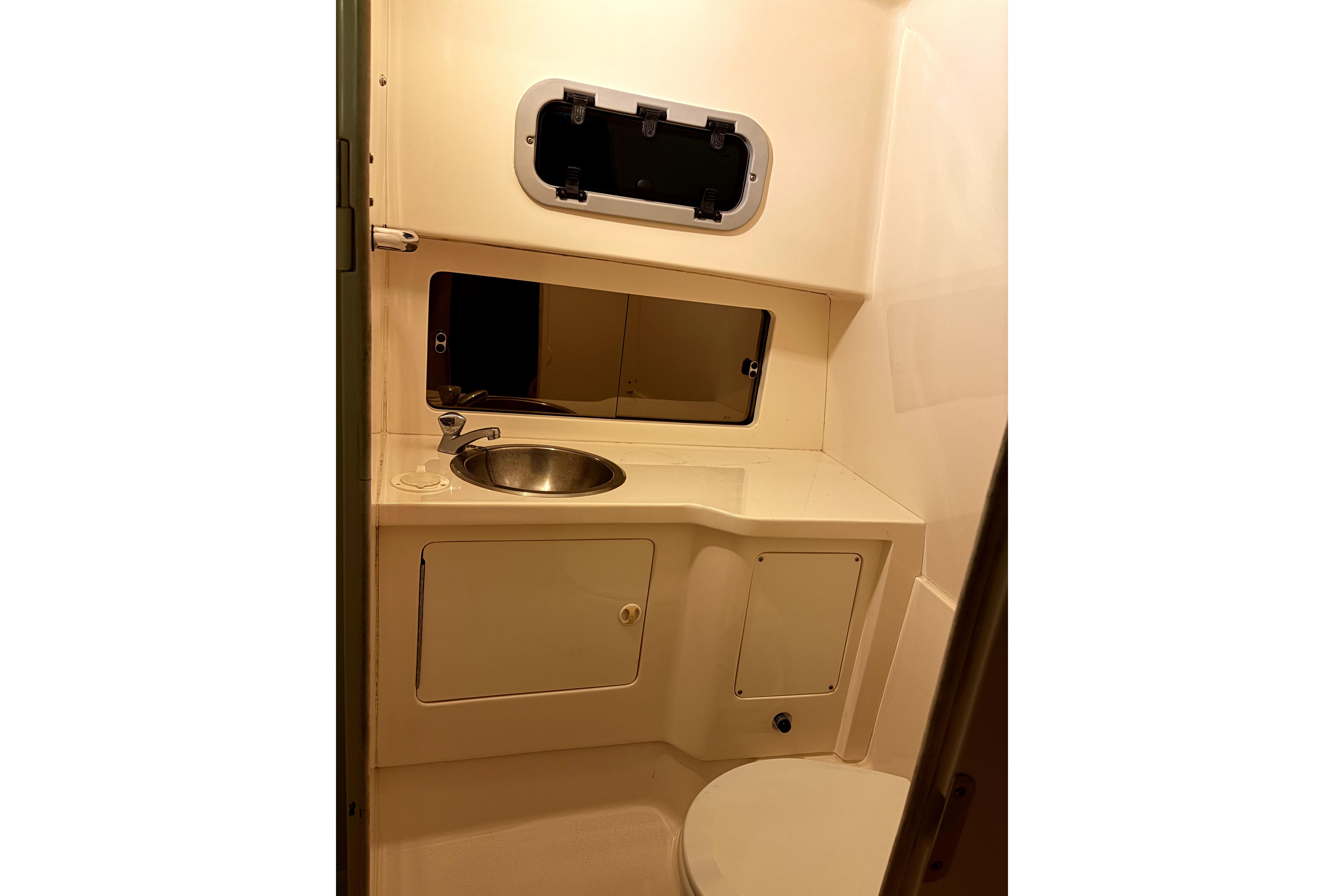 1998 Intrepid 339 Walkaround boat bathroom with sink, mirror, and storage cabinets.
